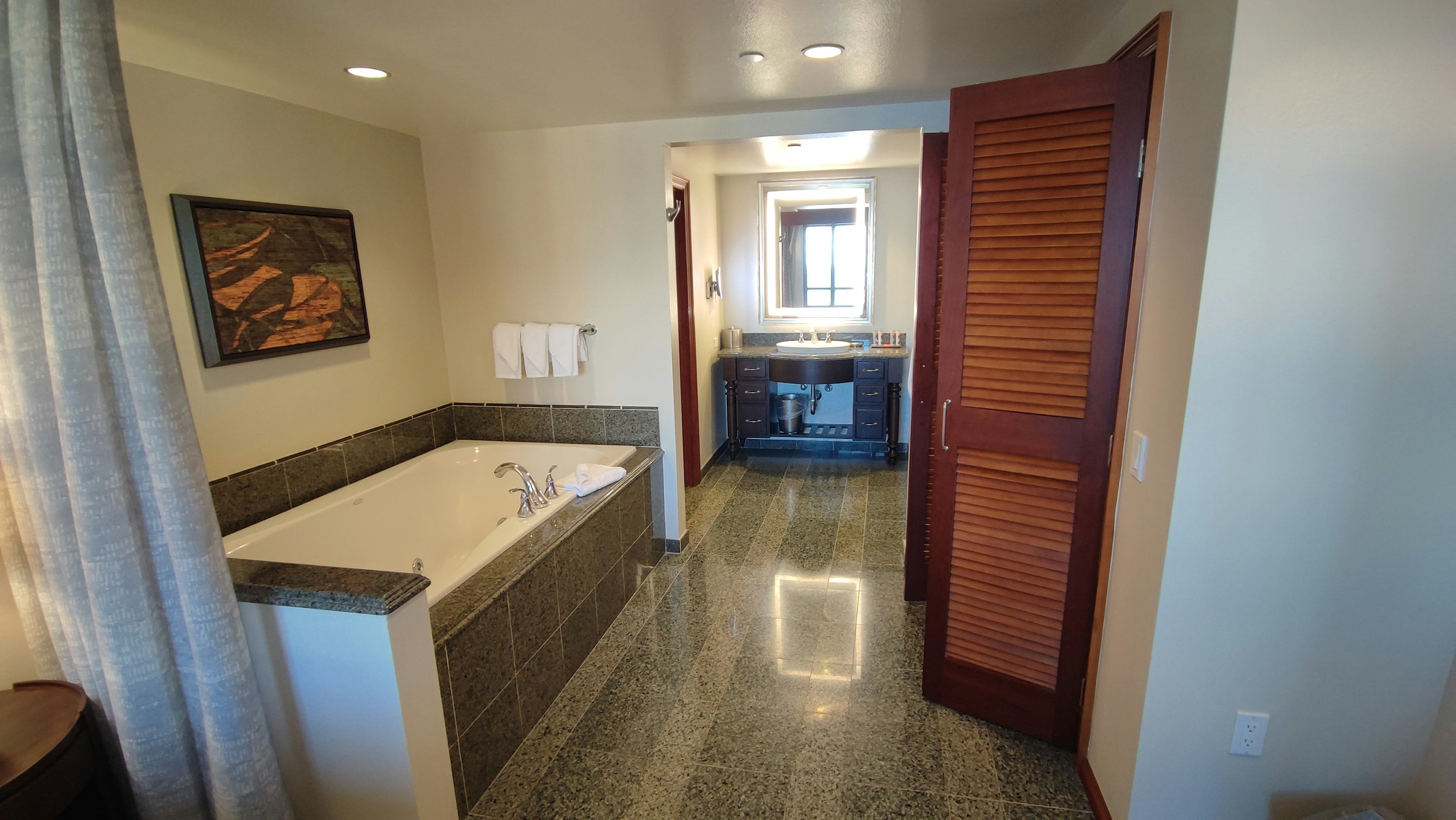 Vista interior de un baño moderno con bañera y encimera de azulejos paredes de colores claros y puerta de madera