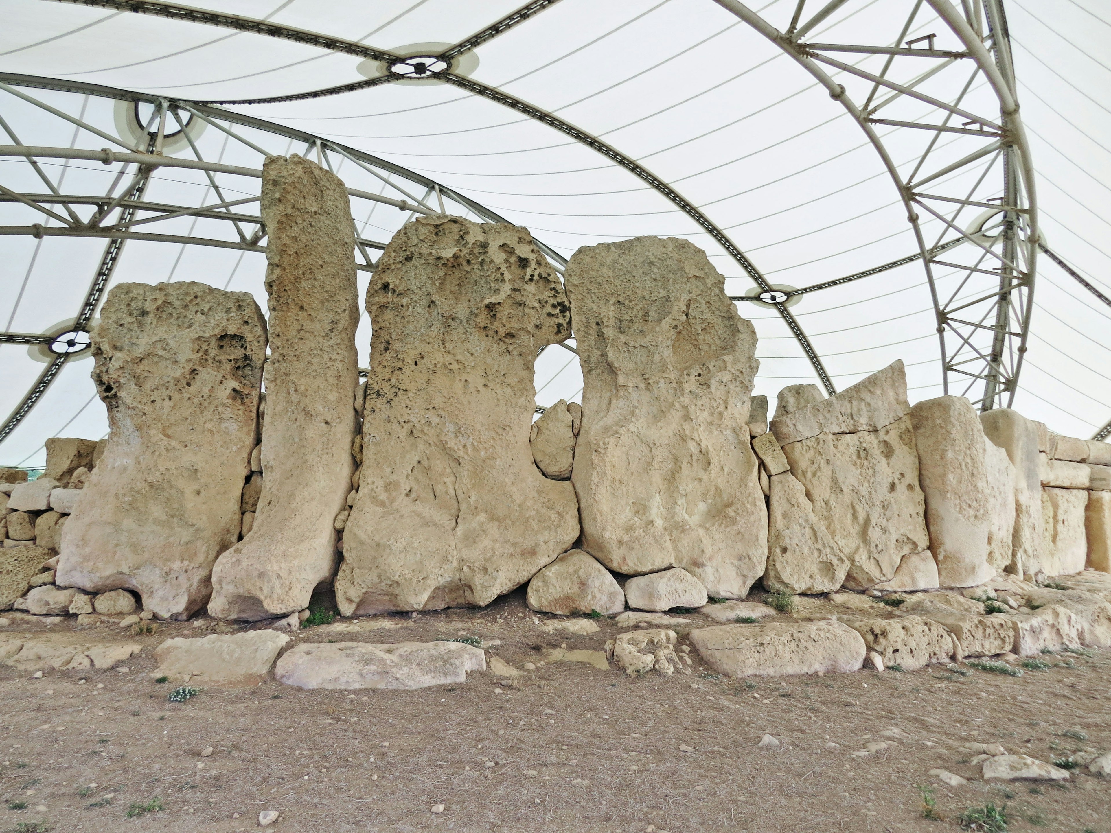 Structure en pierre ancienne sous un abri protecteur montrant de grandes pierres dressées