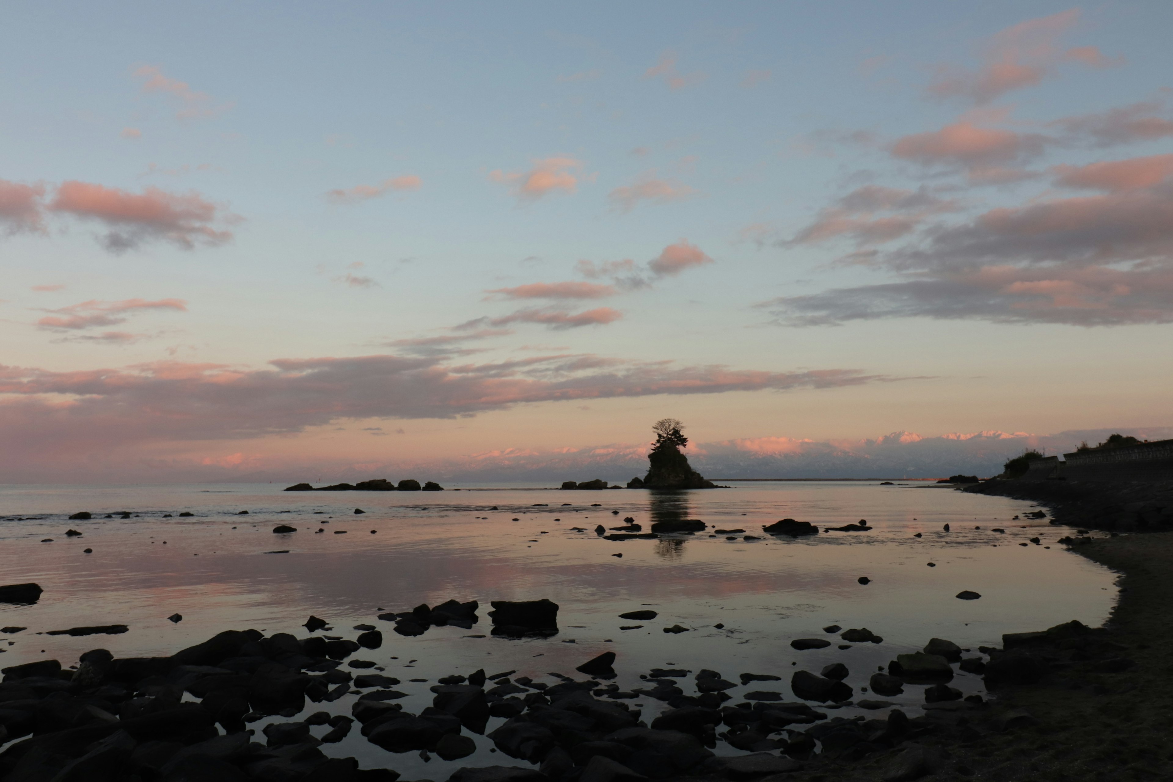 Ruhige Meereslandschaft mit einer kleinen Insel, die sich gegen einen Sonnenuntergangshimmel abhebt