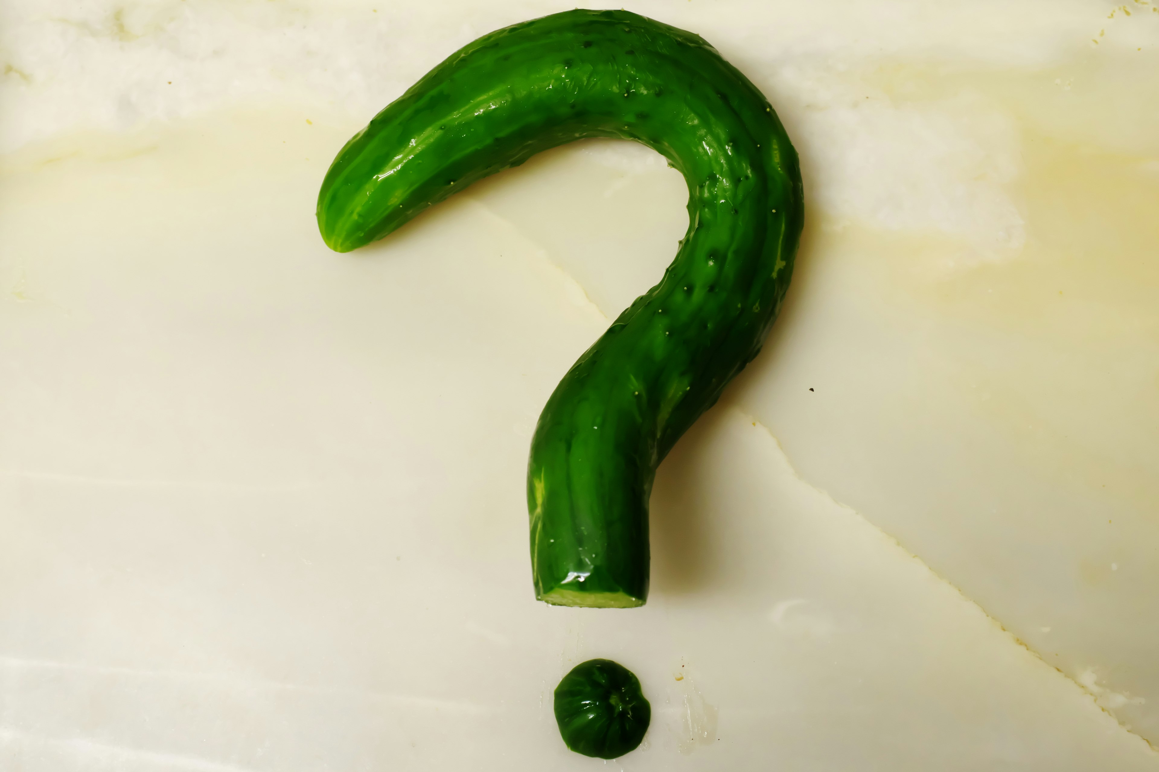 Art piece shaped like a question mark made from a green cucumber