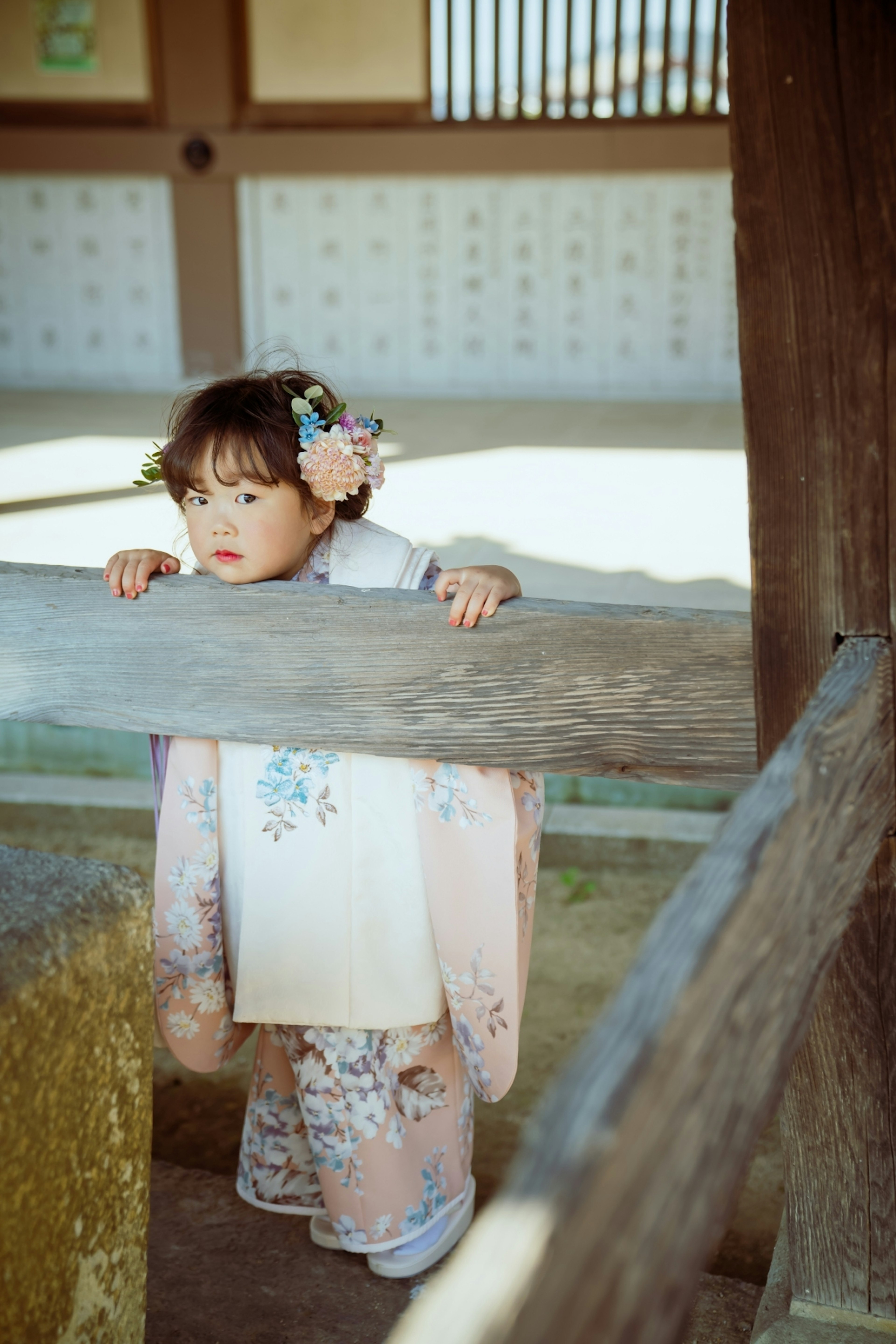 Ein kleines Mädchen im Kimono, das sich an ein Holzgeländer lehnt