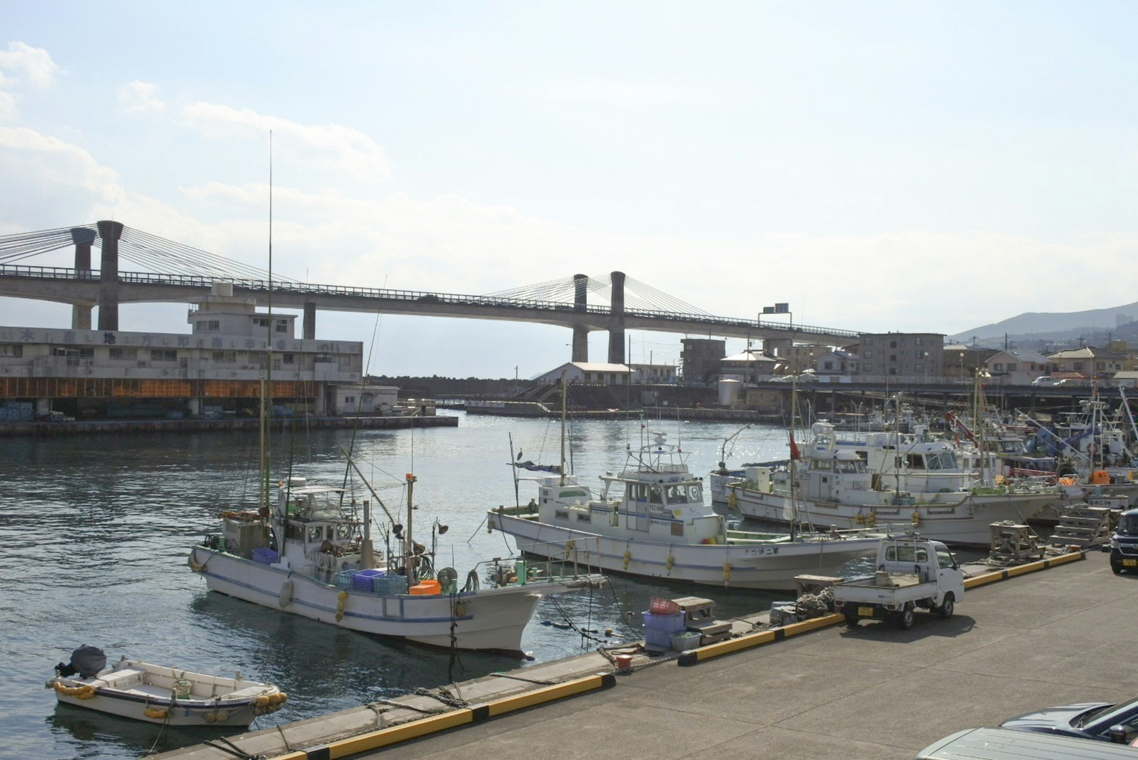 Barcos de pesca atracados en un puerto con un puente al fondo