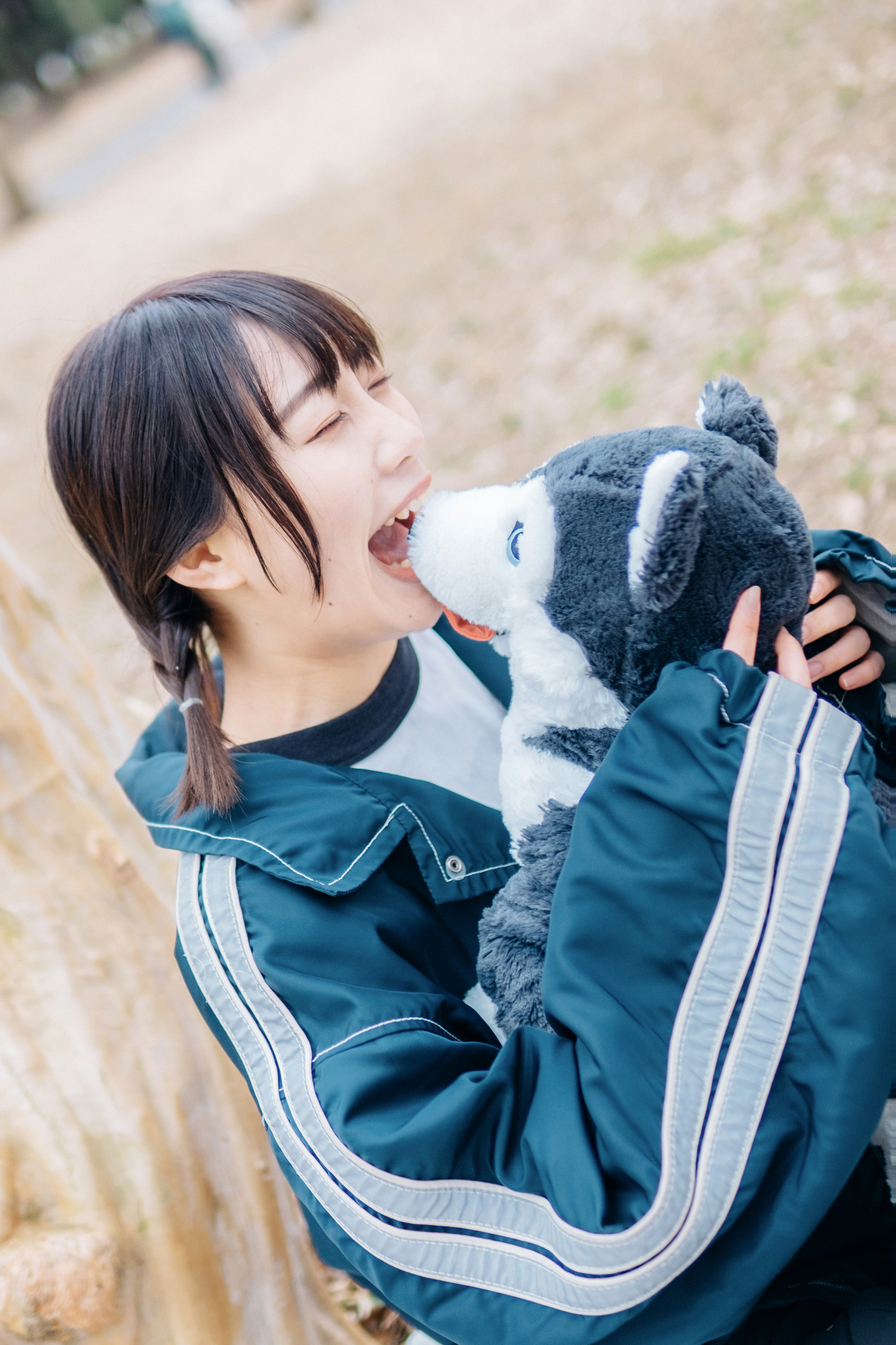 Woman in blue jacket playfully interacting with a wolf plush toy