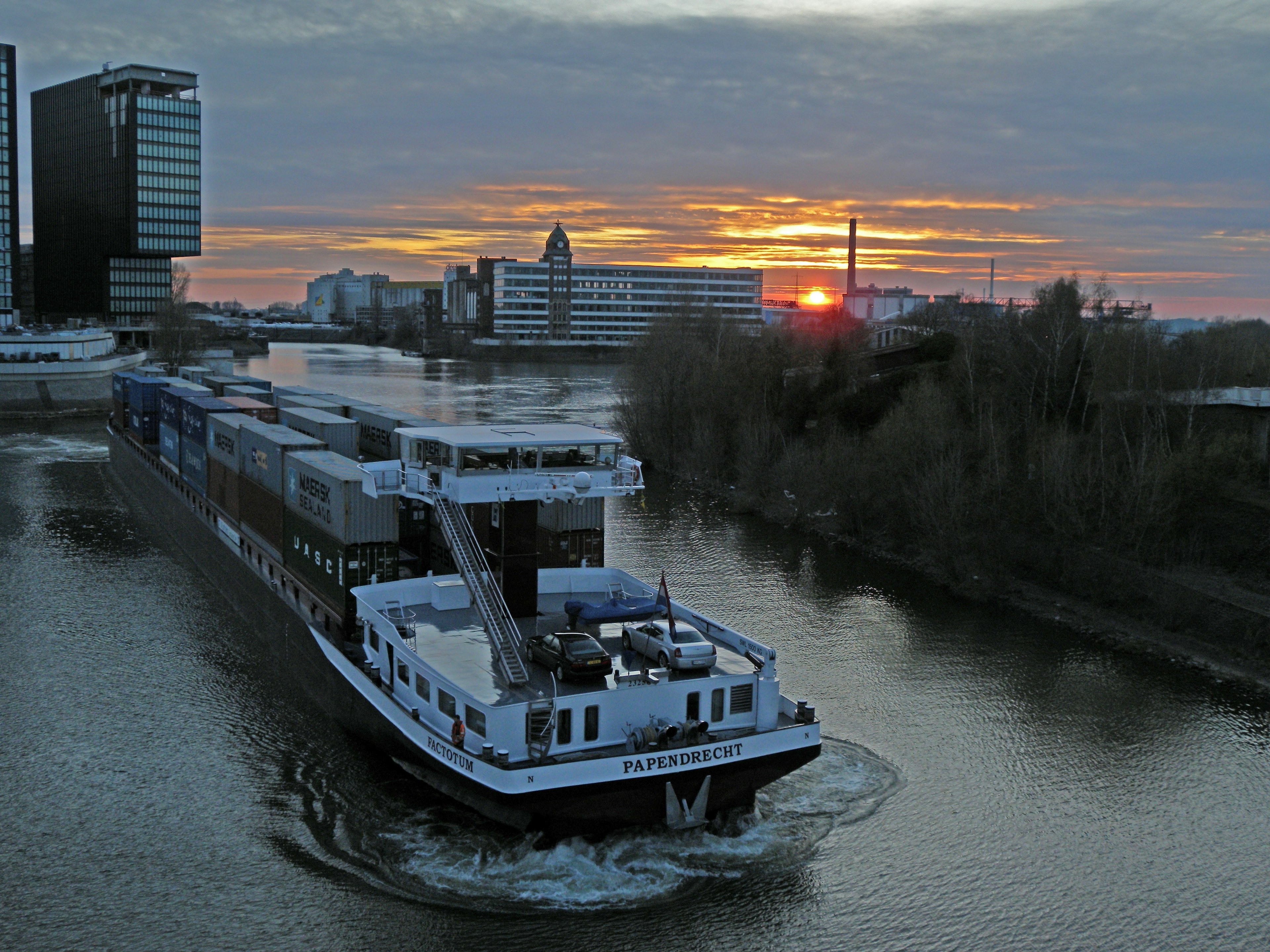 Cargo ship navigating the waterway with a sunset in the background