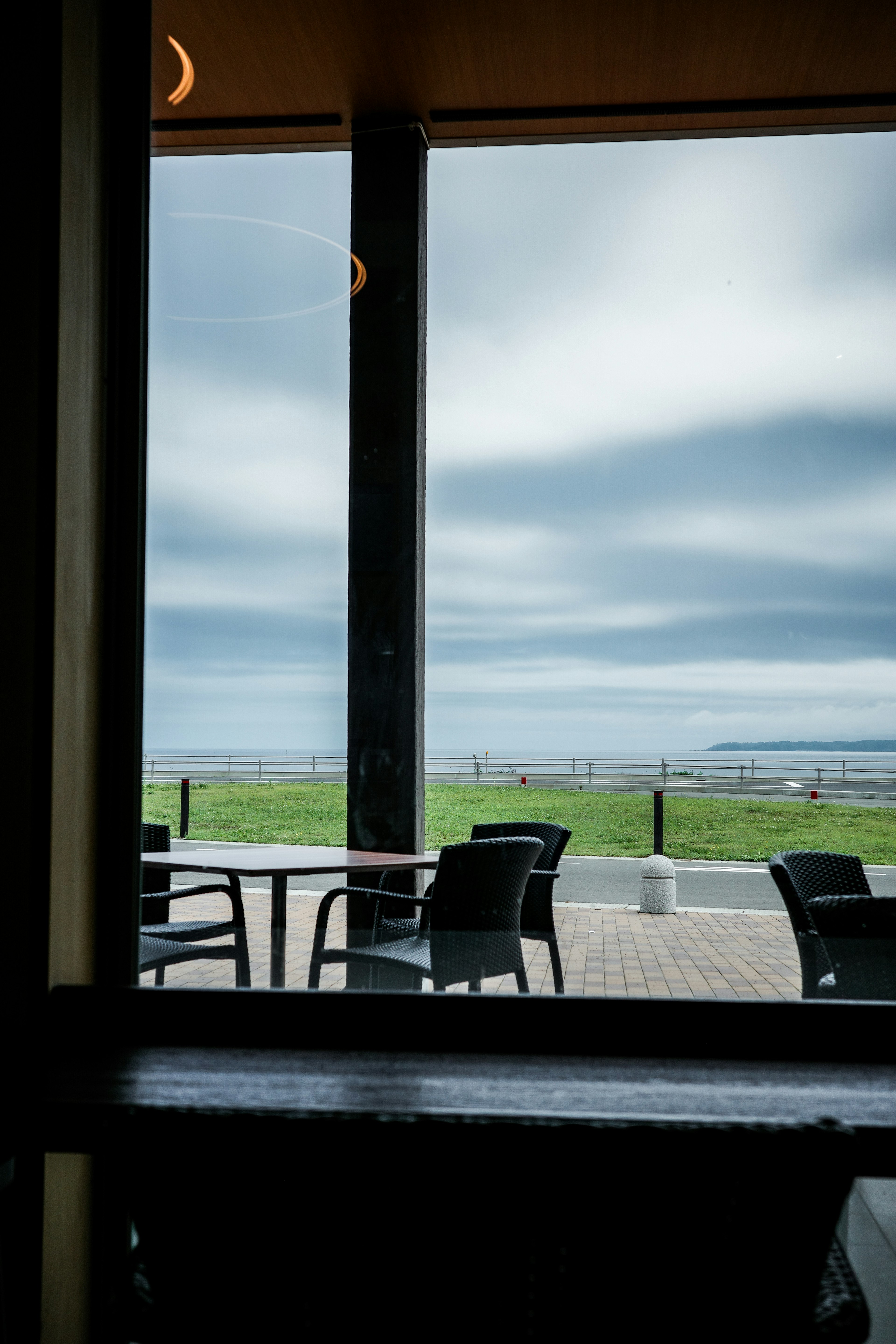 Vista interna di un caffè con paesaggio verde e cielo nuvoloso visibile attraverso la finestra