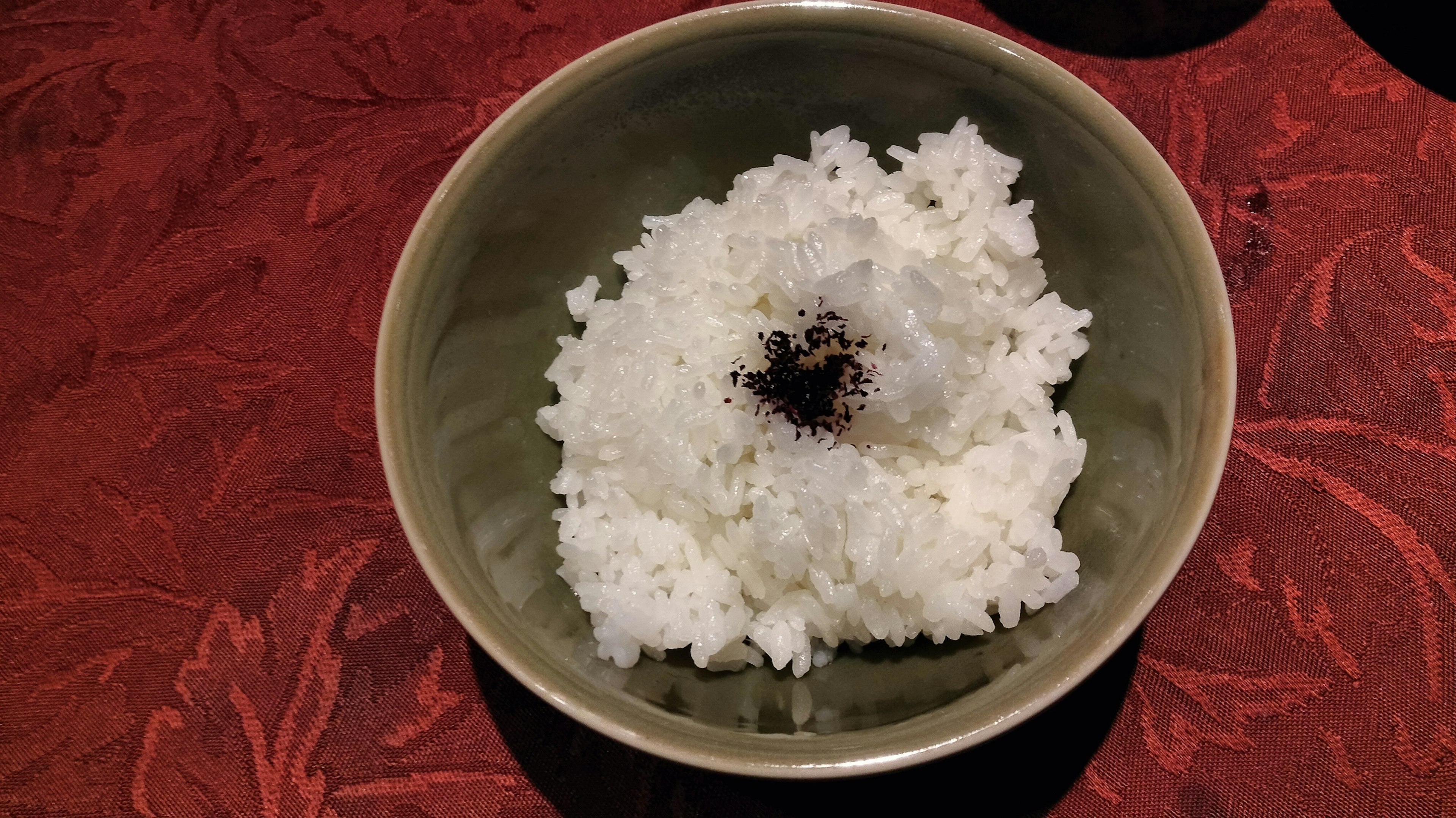 Bol de riz blanc avec une sauce sombre au centre sur une table rouge