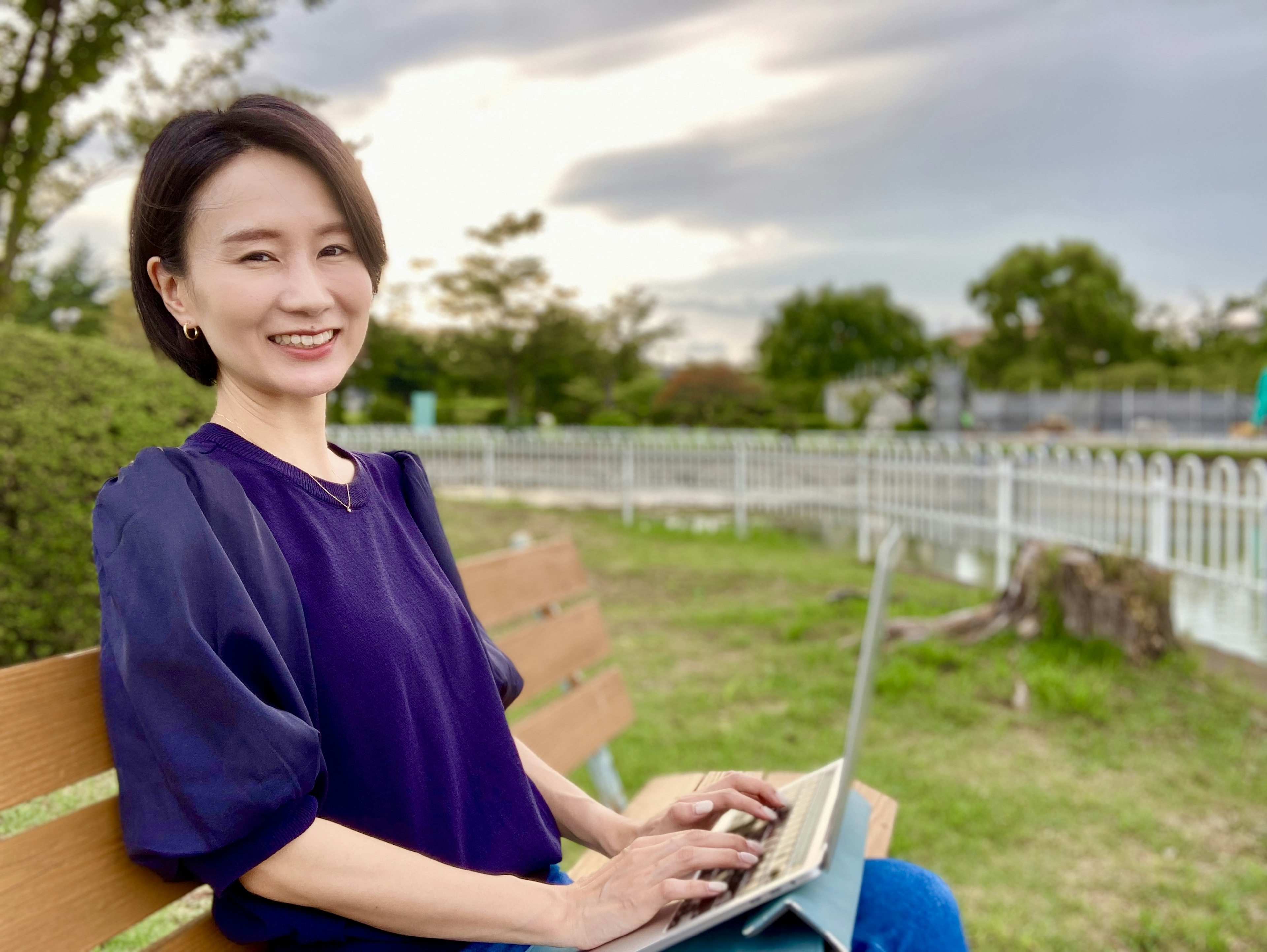 Wanita yang duduk di bangku taman menggunakan laptop