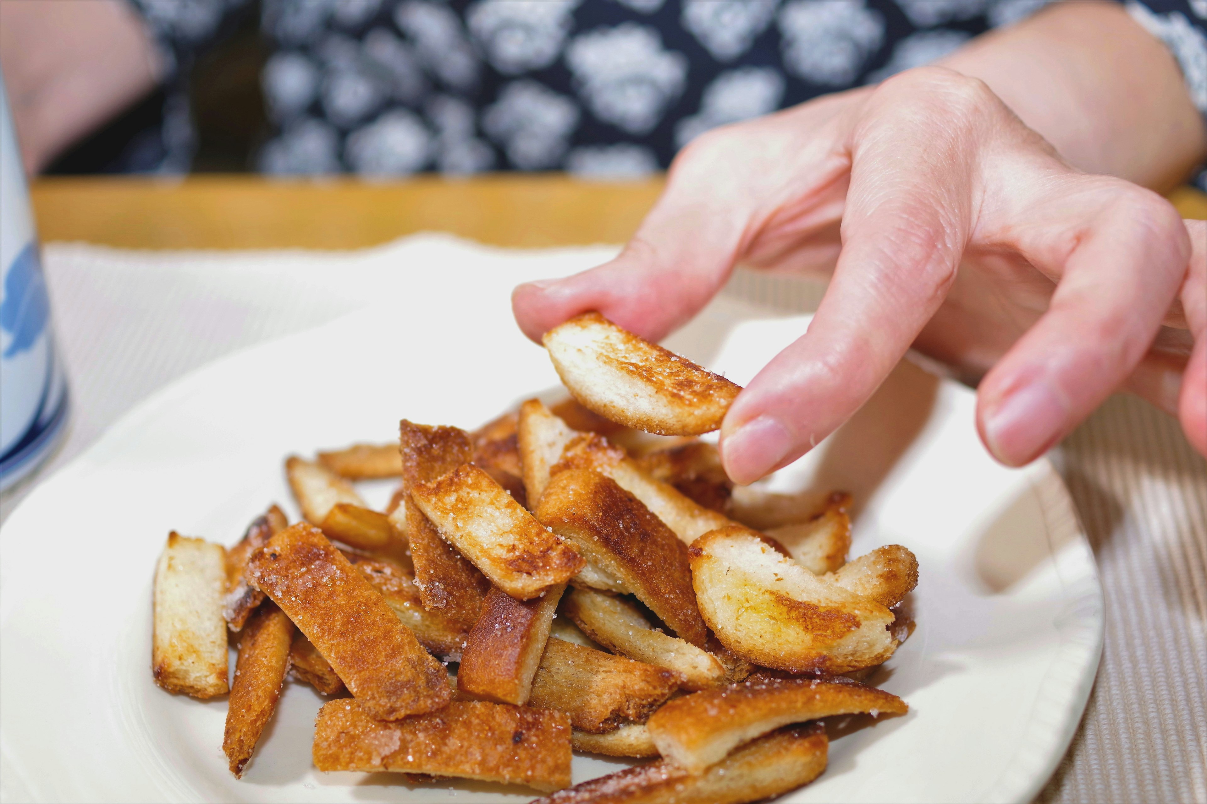 A hand reaching for a stack of crispy fried potato slices