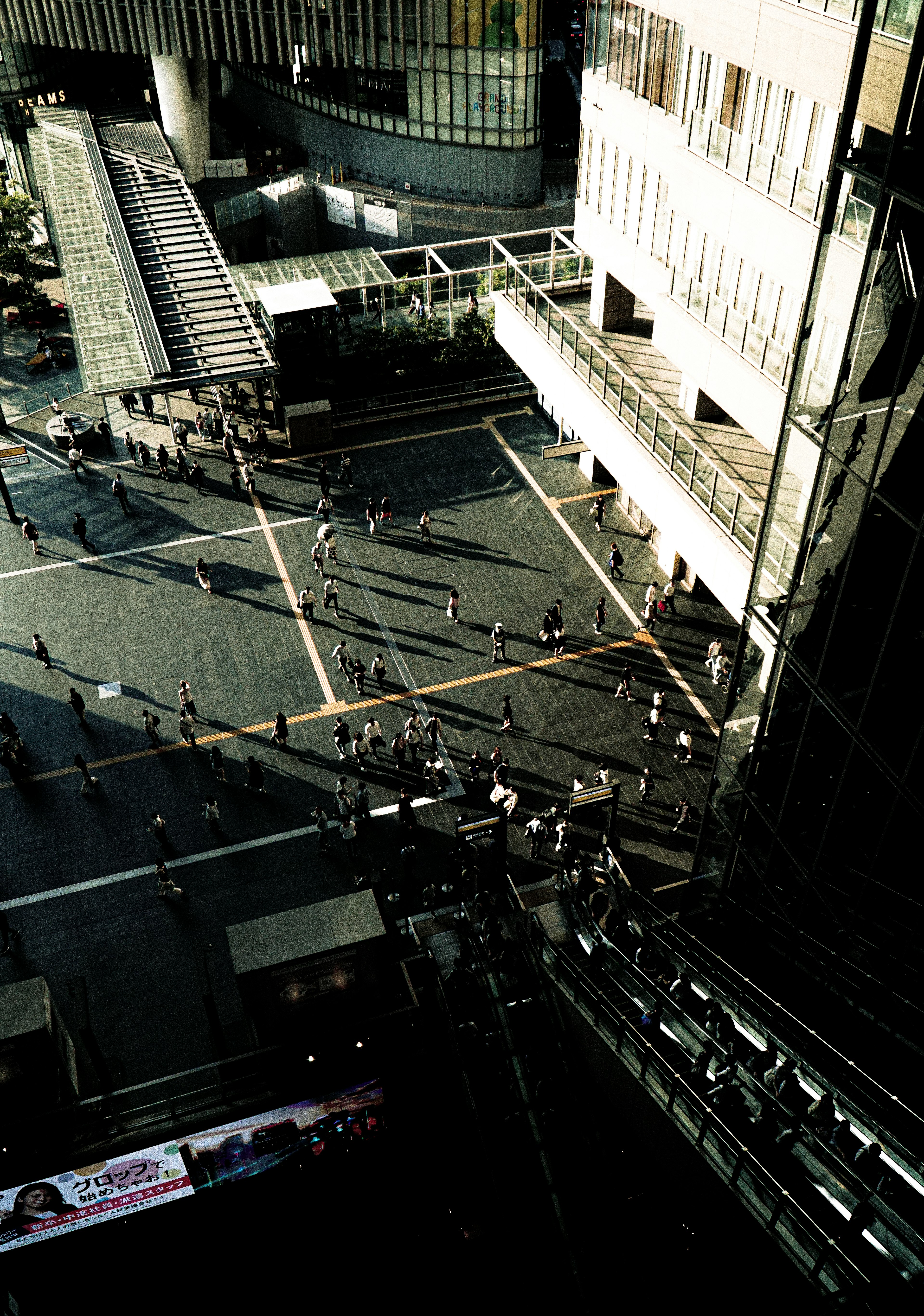 Aerial view of people walking in a plaza between skyscrapers