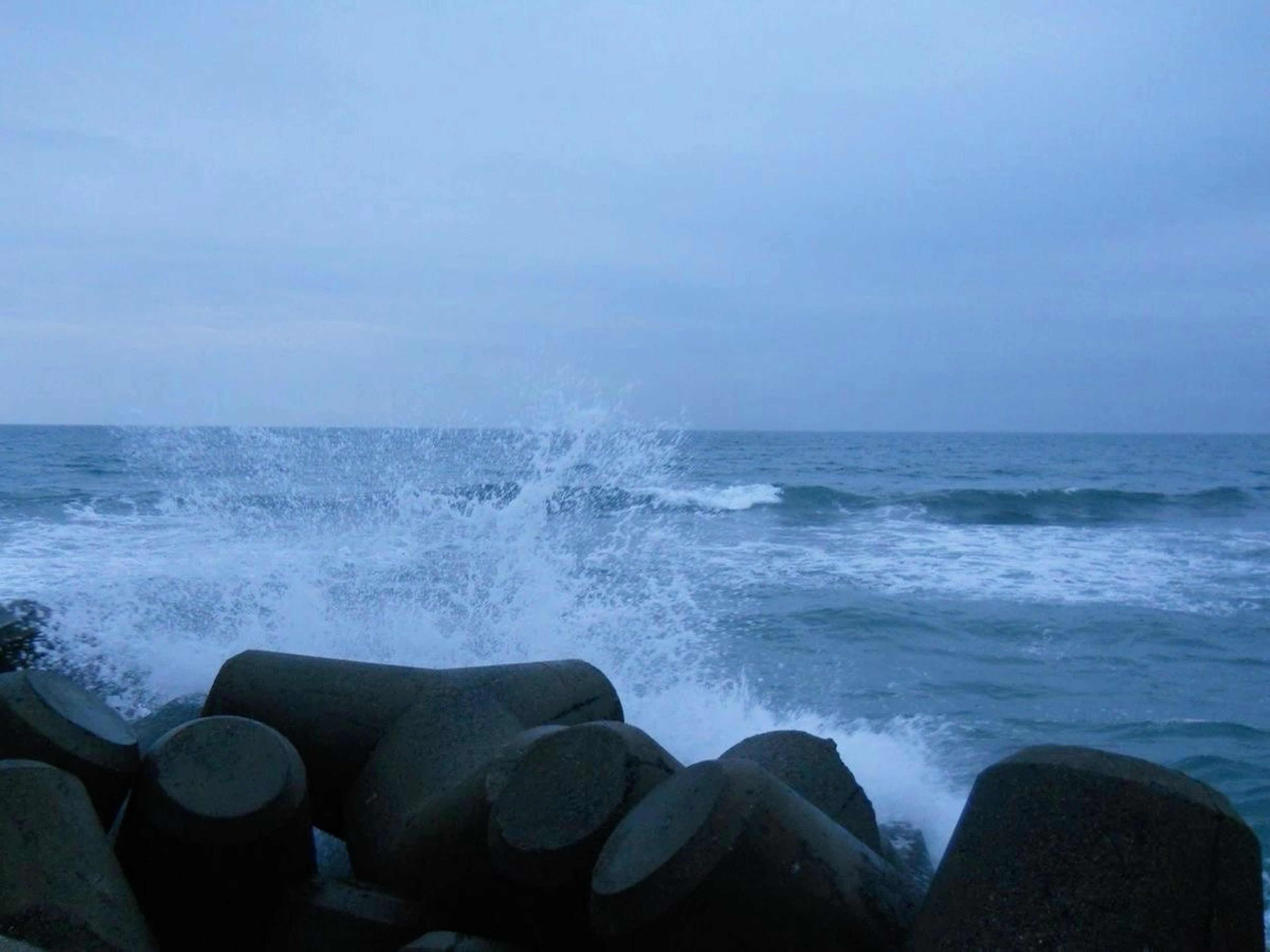 海の波とコンクリートの防波堤の景色