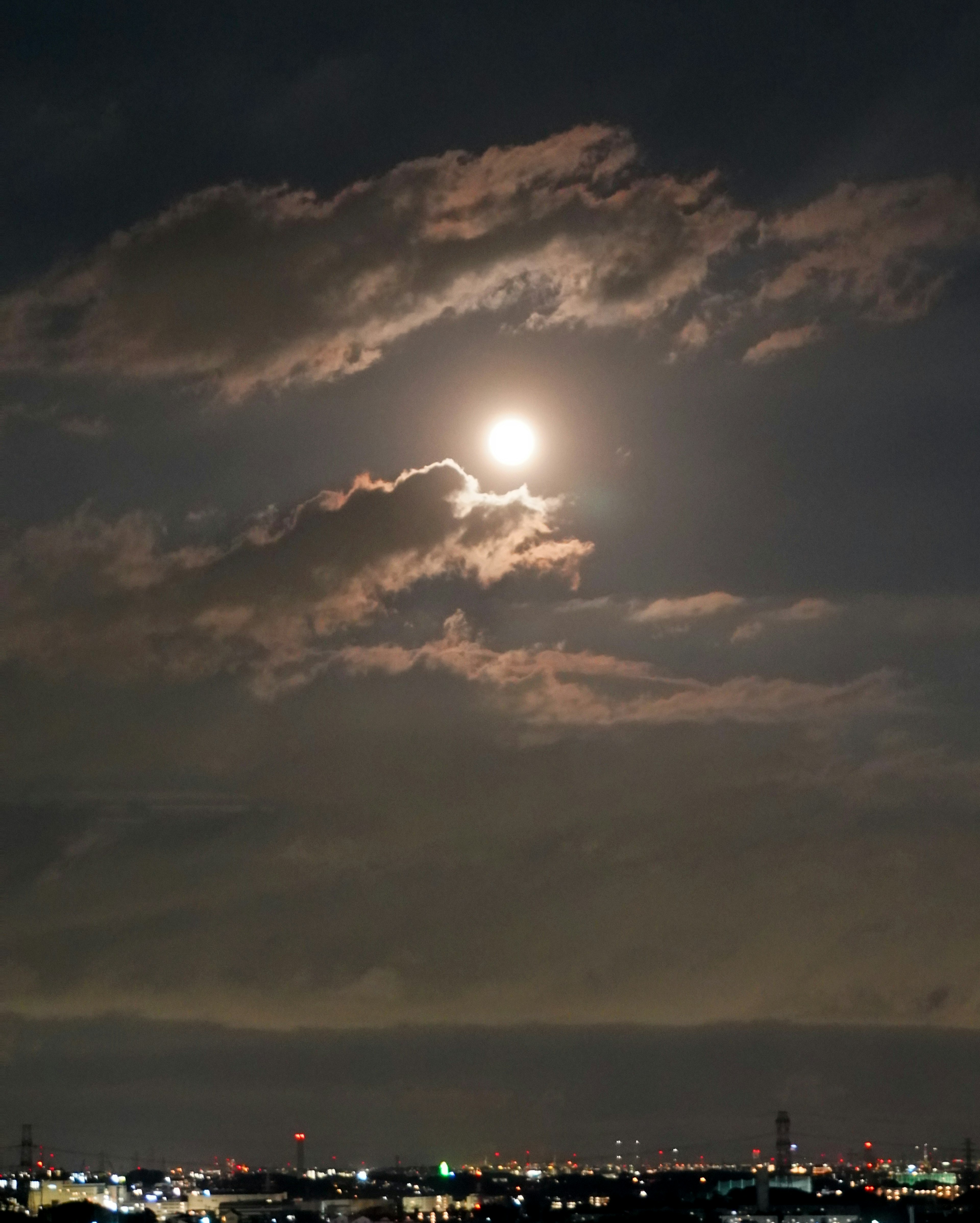 Una vista spettacolare di una luna piena circondata da nuvole nel cielo notturno