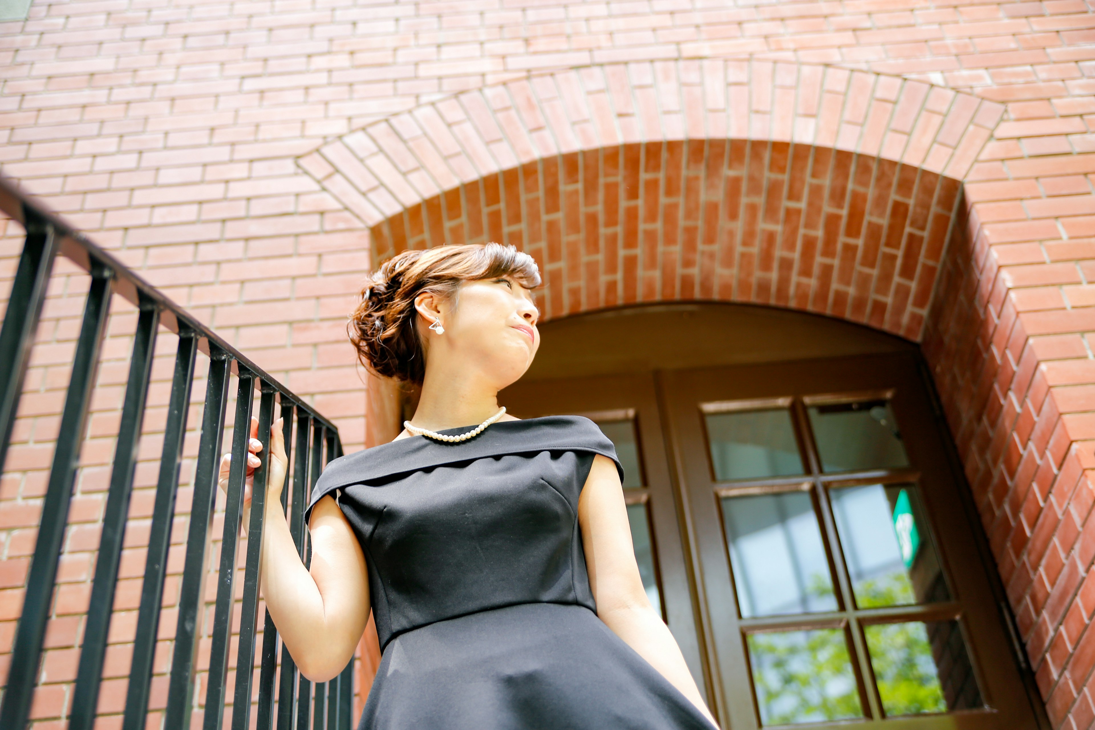 穿著黑色連衣裙的女人站在磚砌建築前