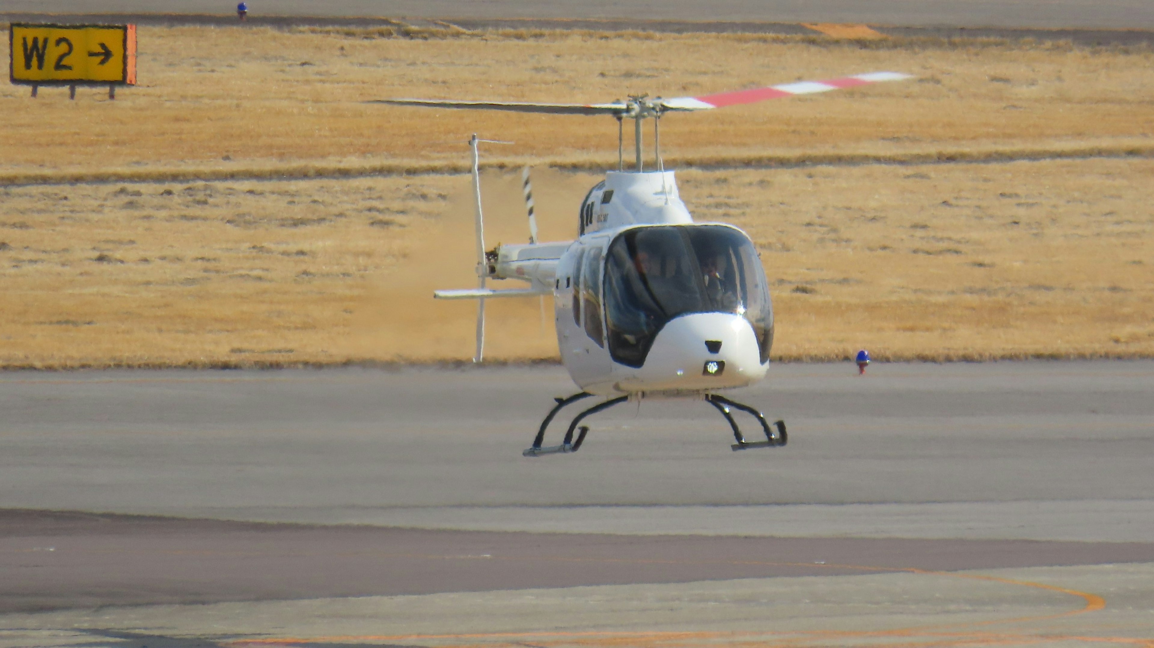 A white and black helicopter is parked on the runway