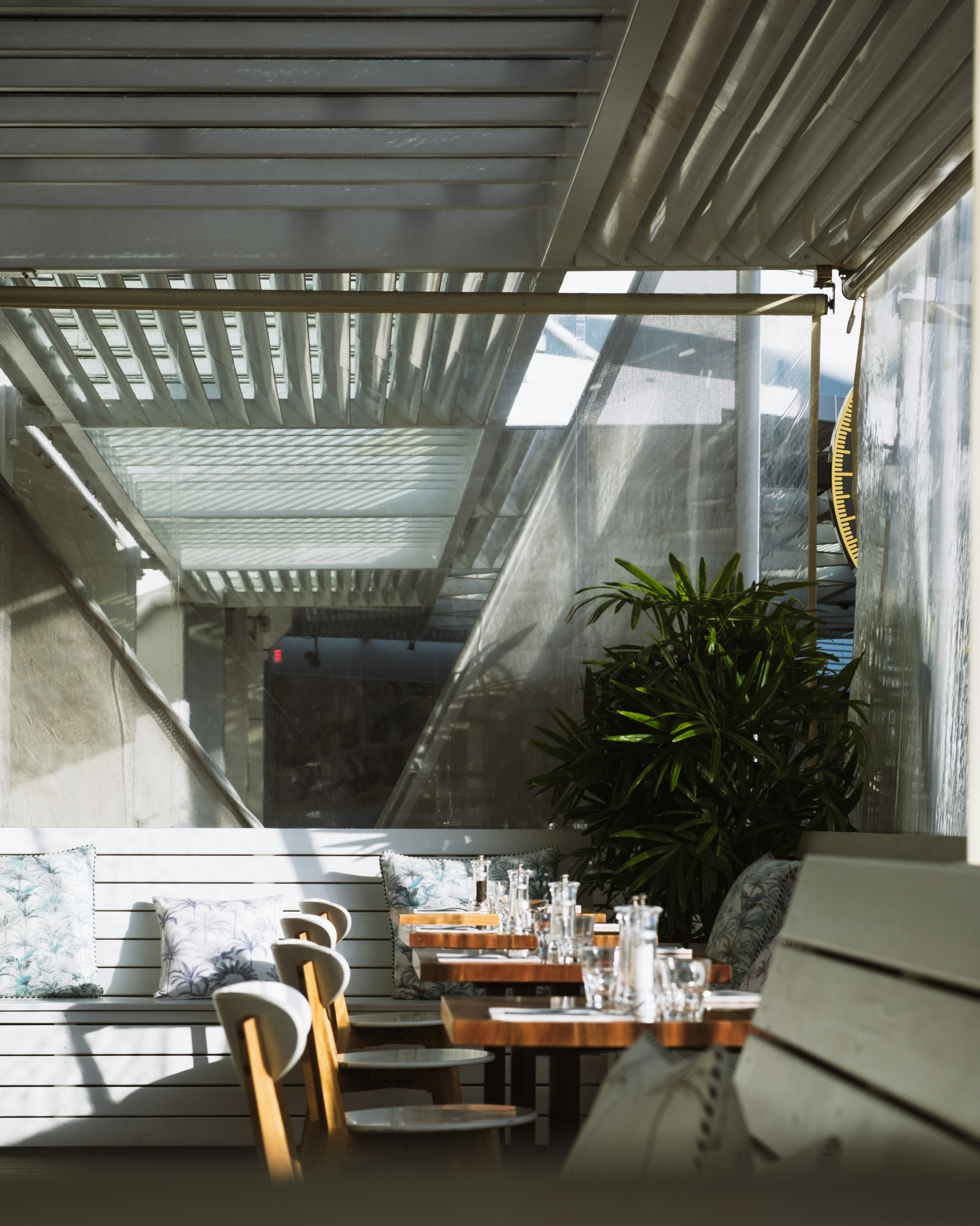 Bright café terrace with tables and chairs decorated with greenery