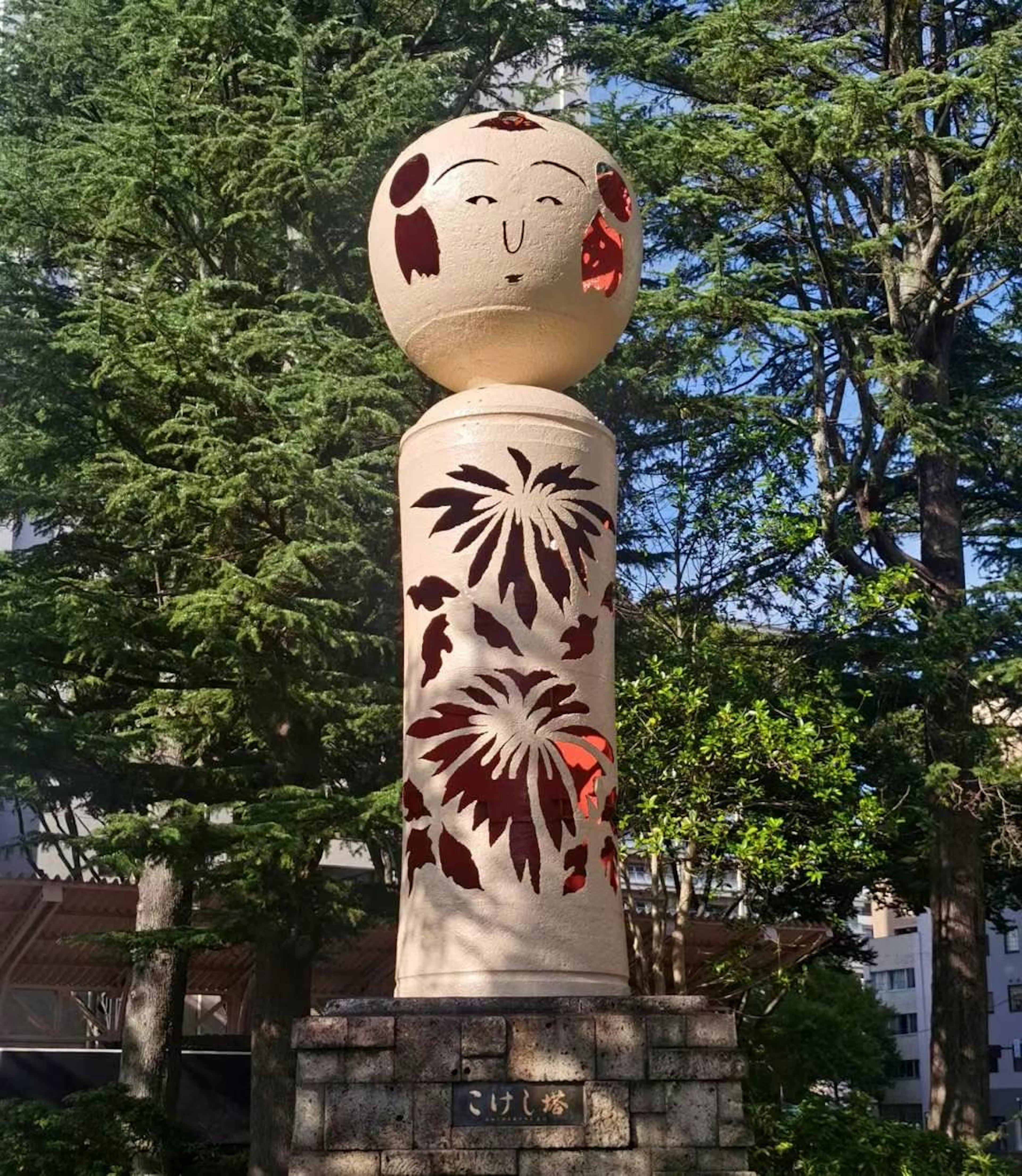 Wooden sculpture with red floral patterns featuring a smiling face