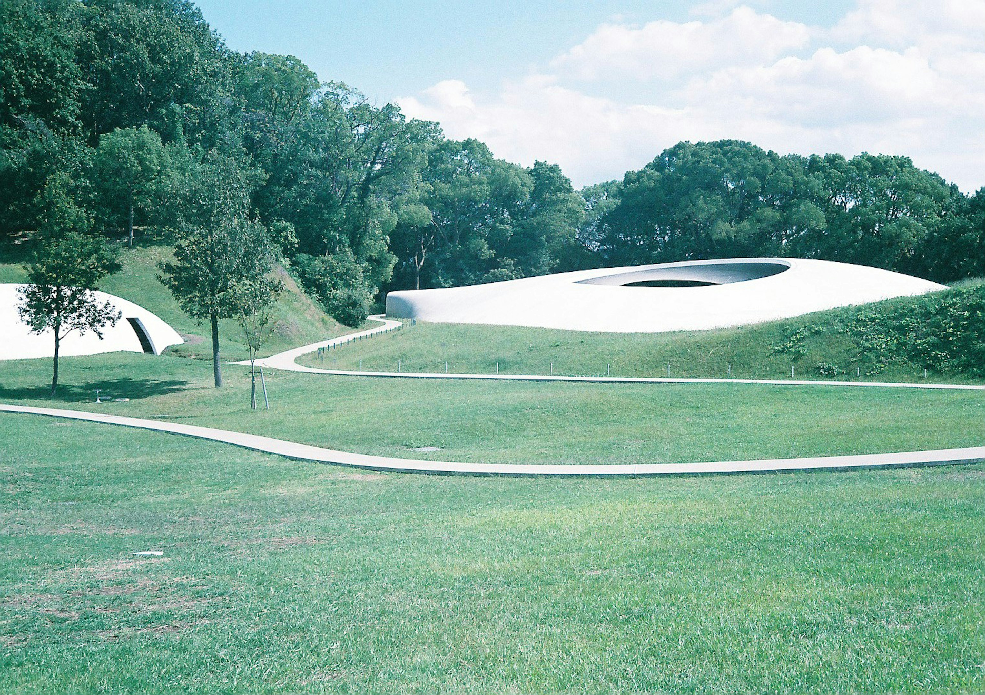 Strutture architettoniche moderne in un parco verdeggiante con sentieri tortuosi