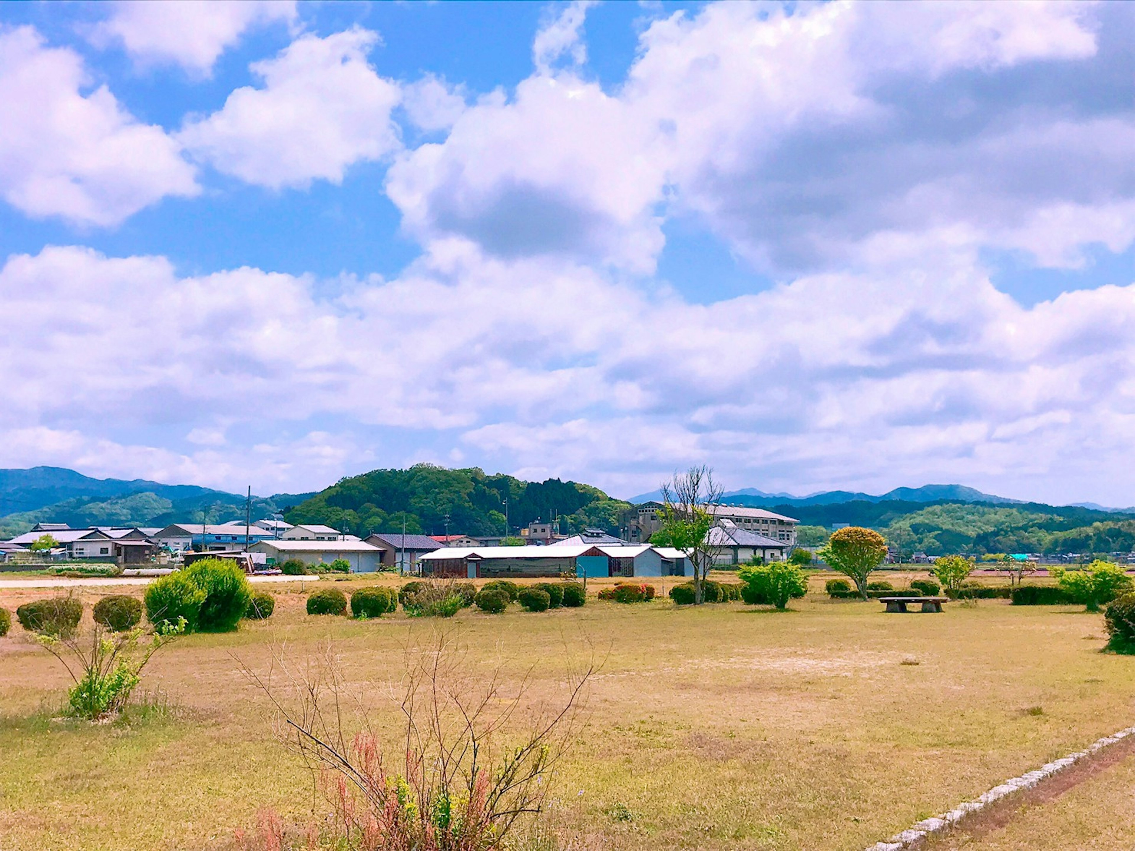 Vista escénica de cielo azul y nubes blancas sobre un pueblo y colinas