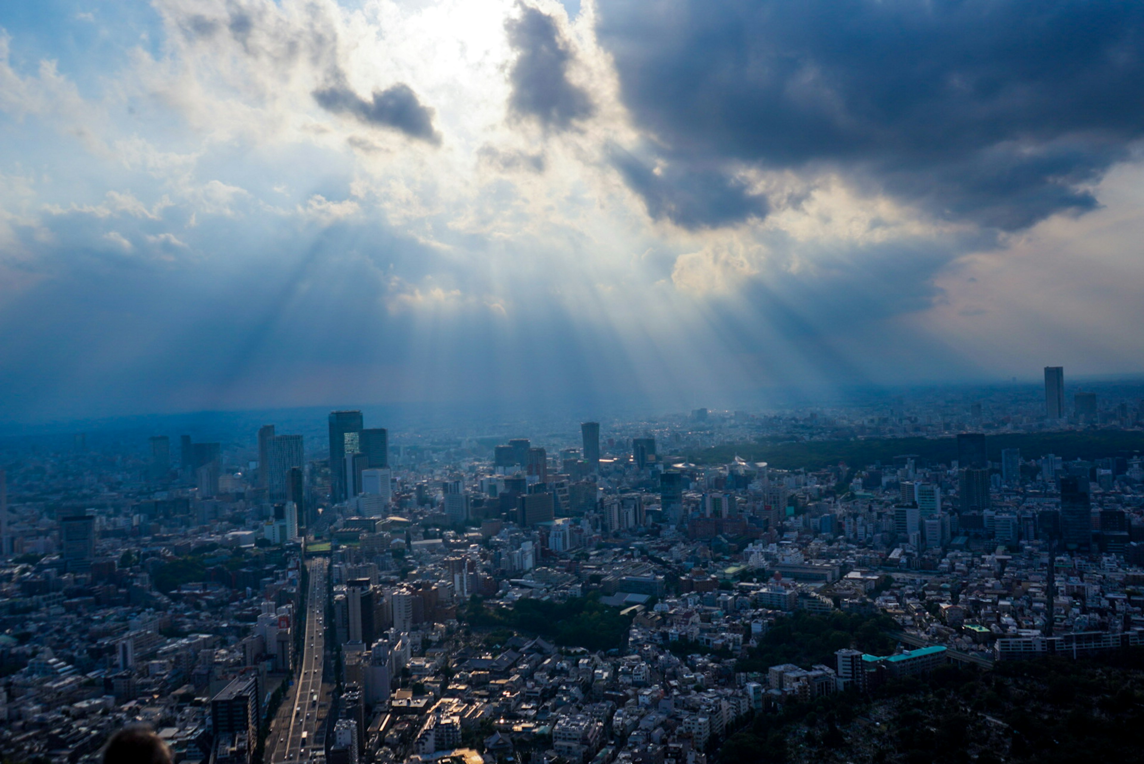 東京の都市景観と雲に覆われた空から差し込む光