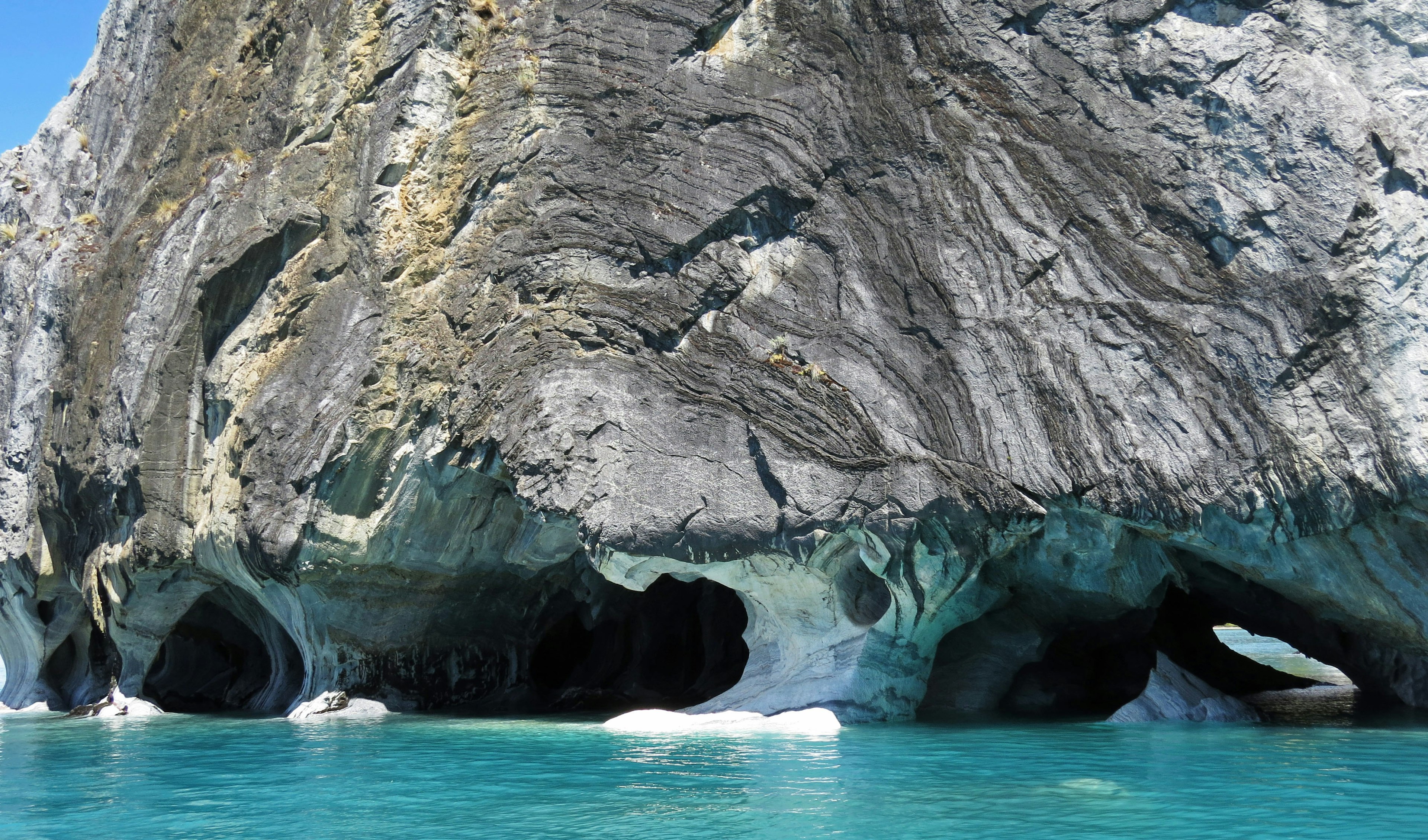 Large rock formation with caves near turquoise water