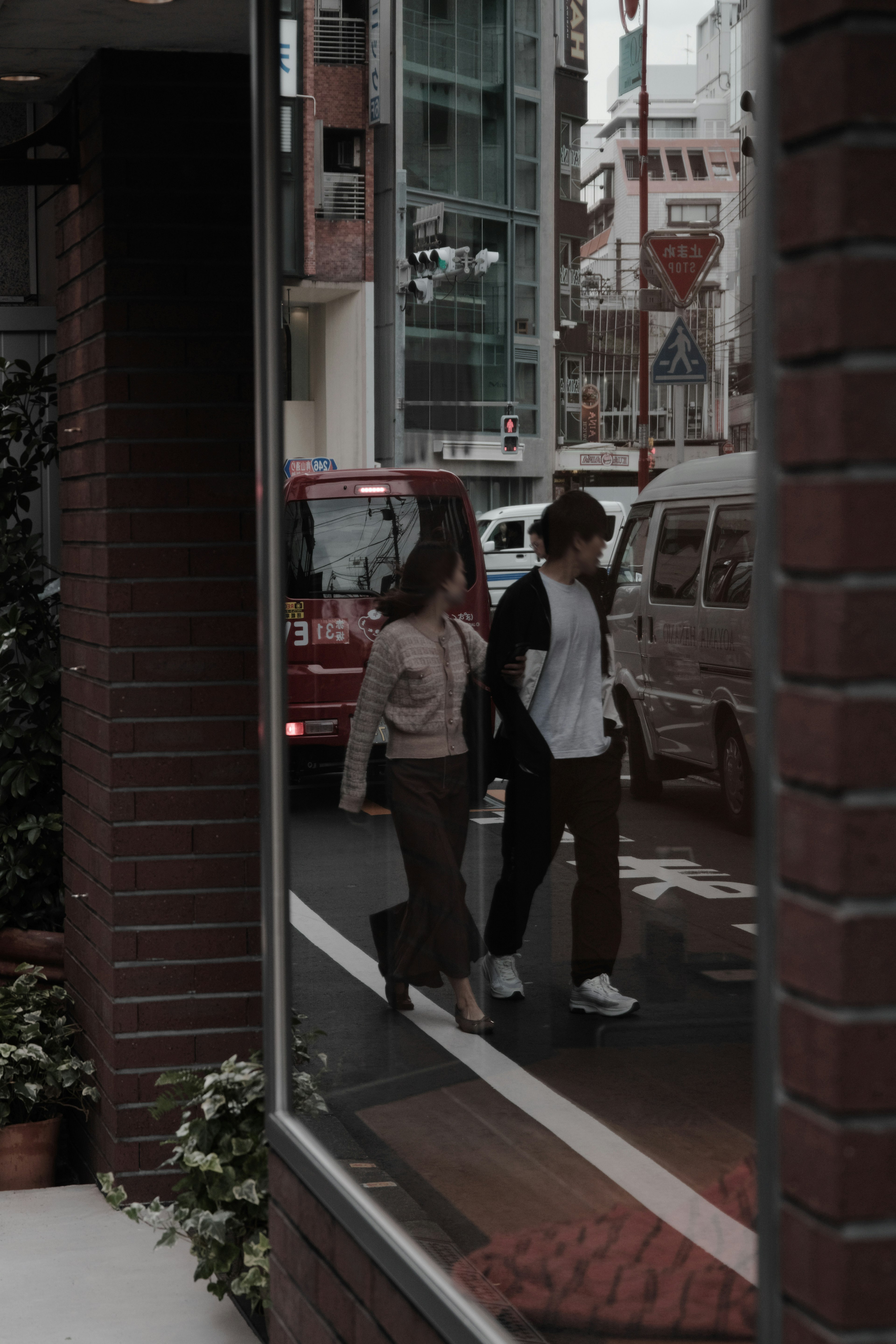 Reflet d'un couple traversant la rue dans une fenêtre