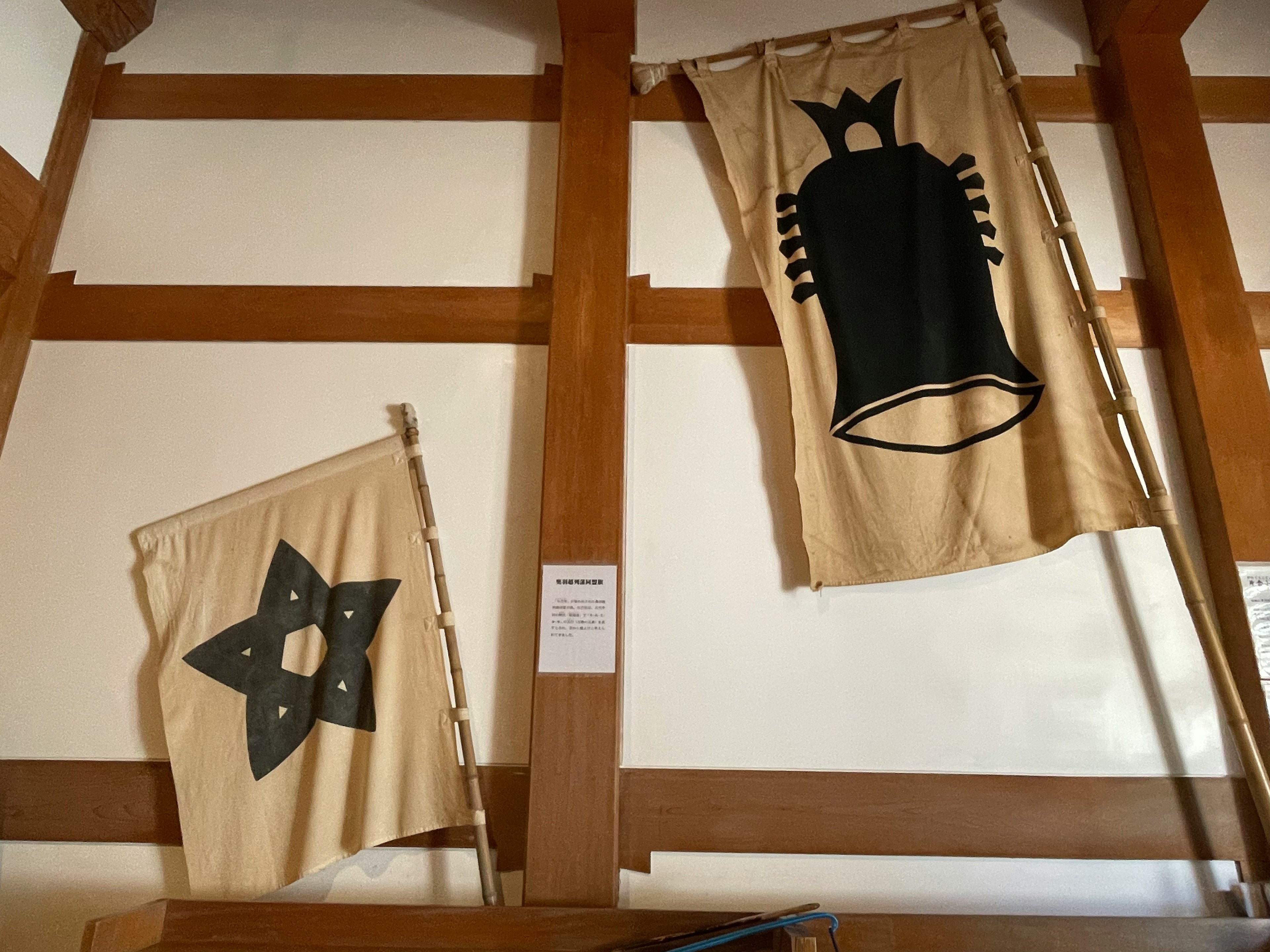 Una imagen que presenta dos banderas colgadas en una pared Una bandera tiene un diseño de estrella y la otra muestra la silueta de una campana