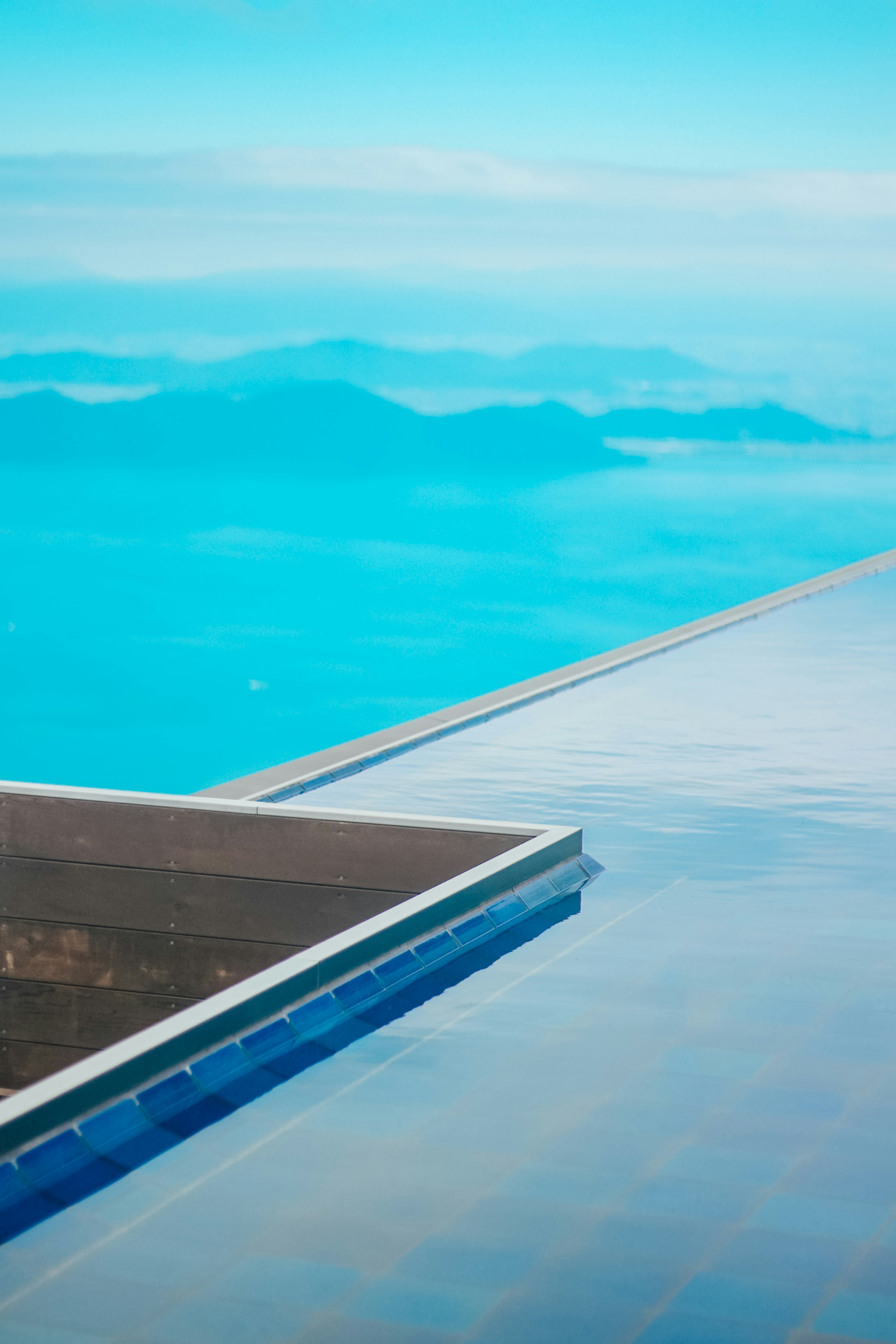 Bord d'une piscine surplombant des montagnes et un ciel bleu