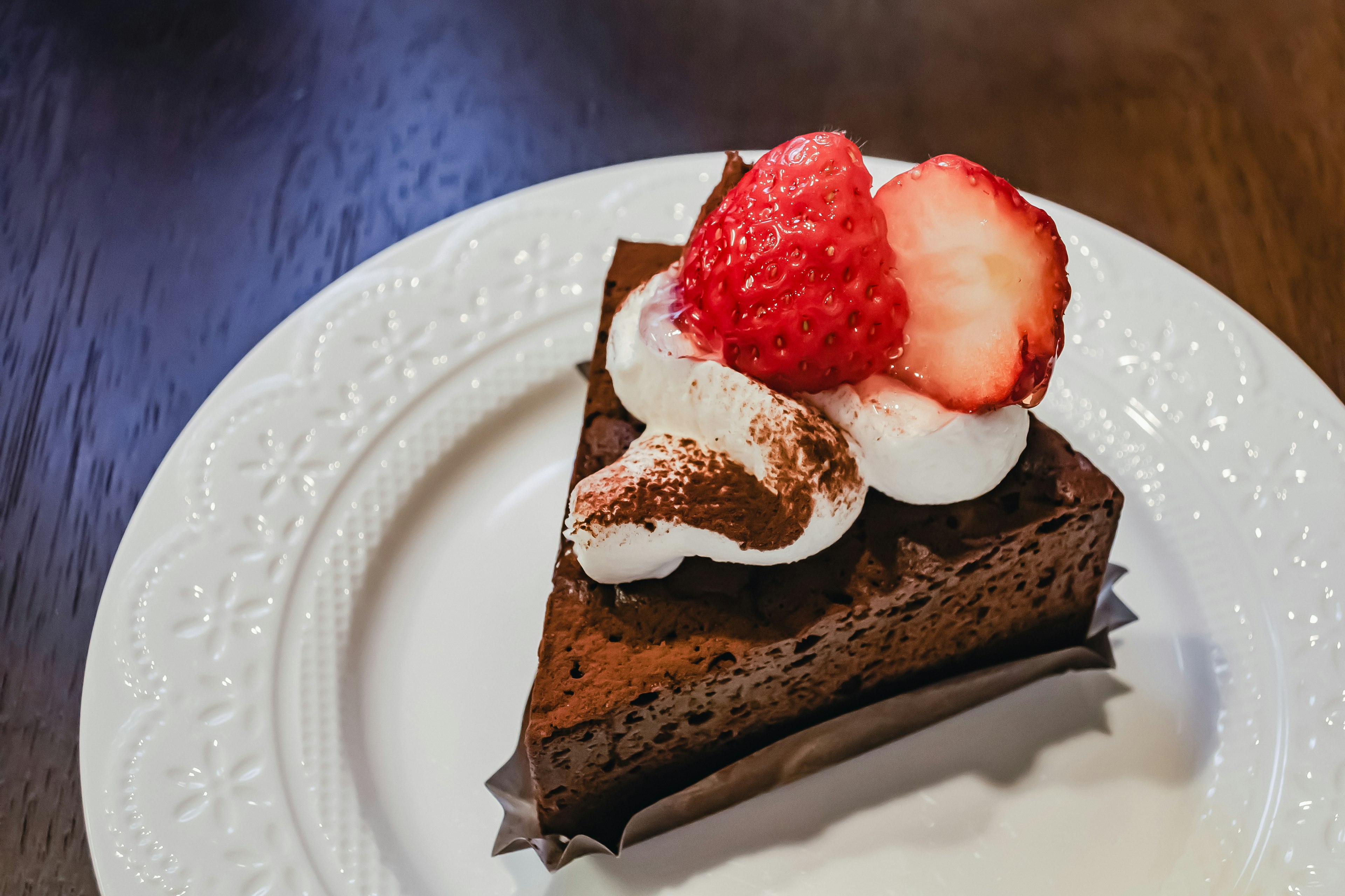 Slice of chocolate cake topped with whipped cream and strawberries