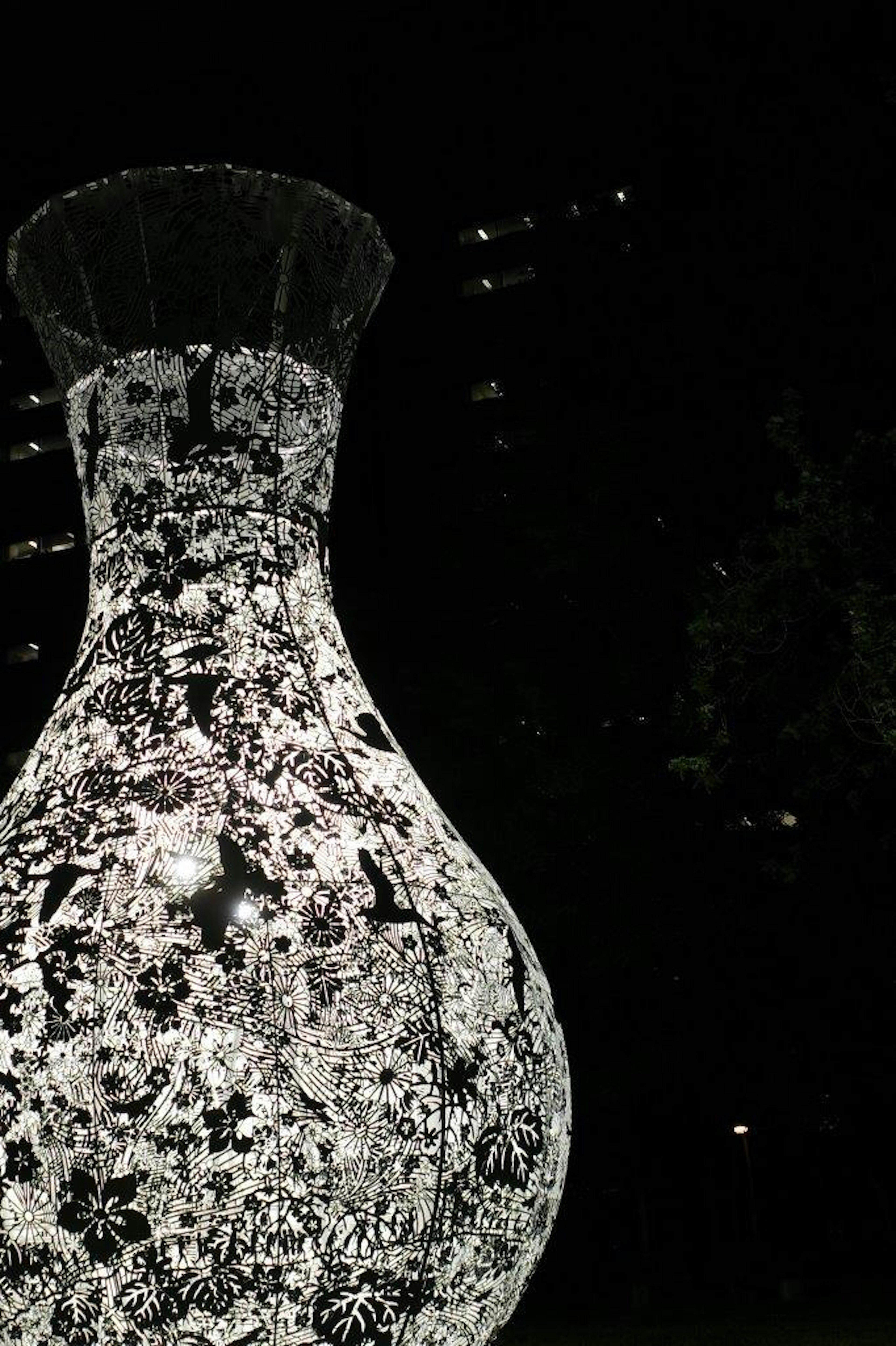 Decorative vase-shaped object in black and white against a dark background