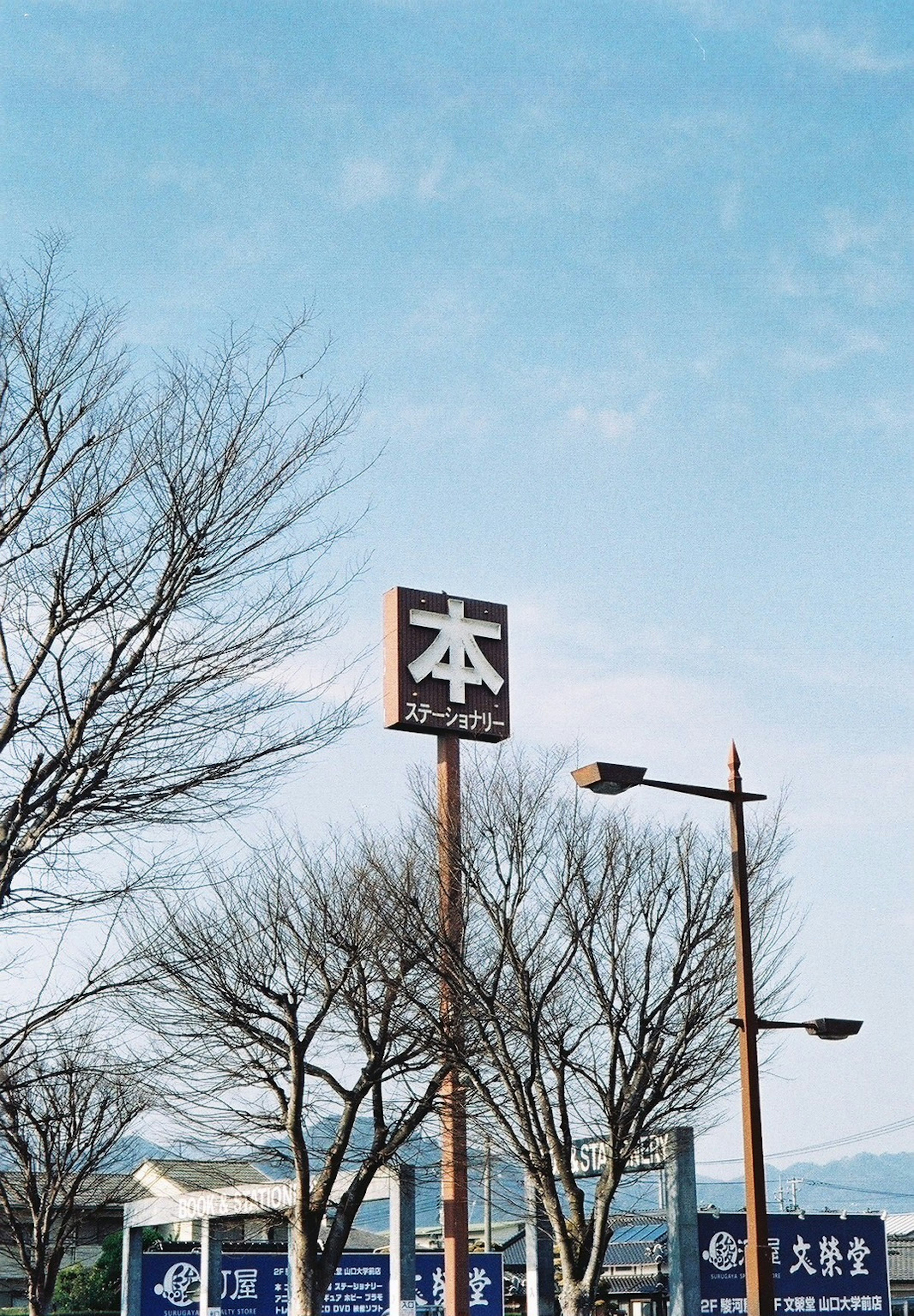 Schild für eine Buchhandlung unter einem blauen Himmel mit Bäumen