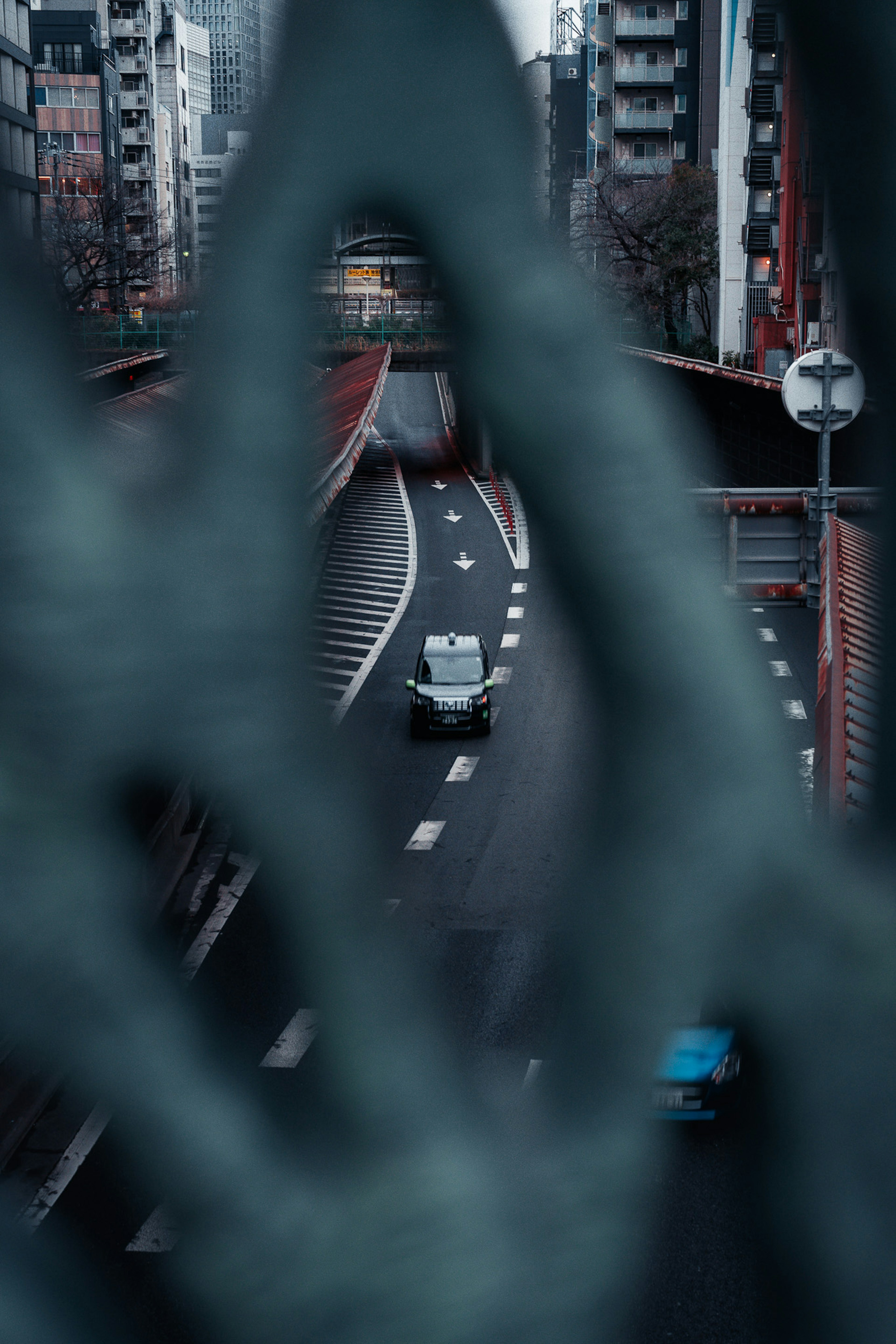 鉄のフェンス越しに見える都市の道路と車