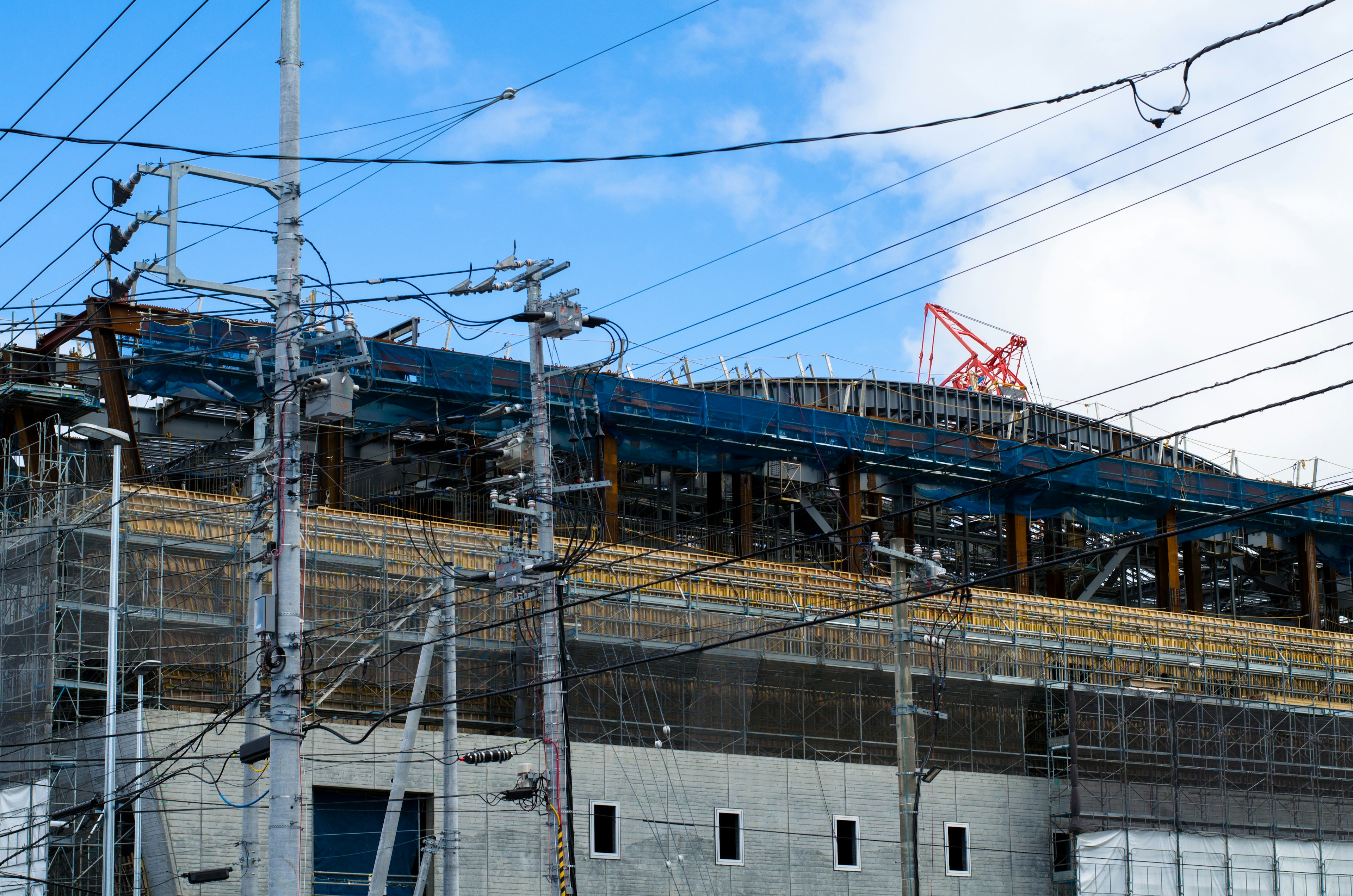 Sitio de construcción con edificio visible y líneas eléctricas bajo un cielo azul