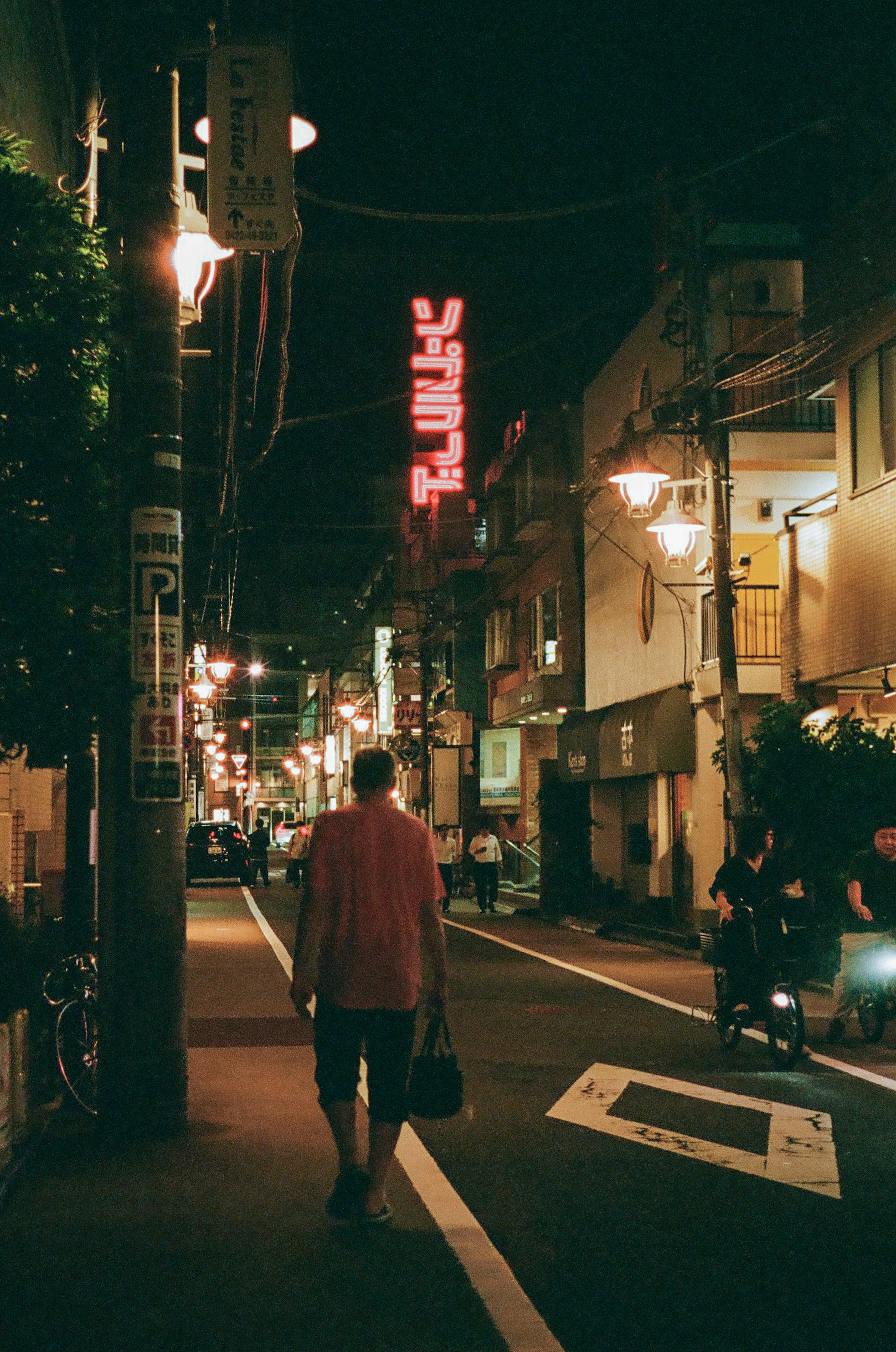 Man walking in a night street illuminated by neon lights