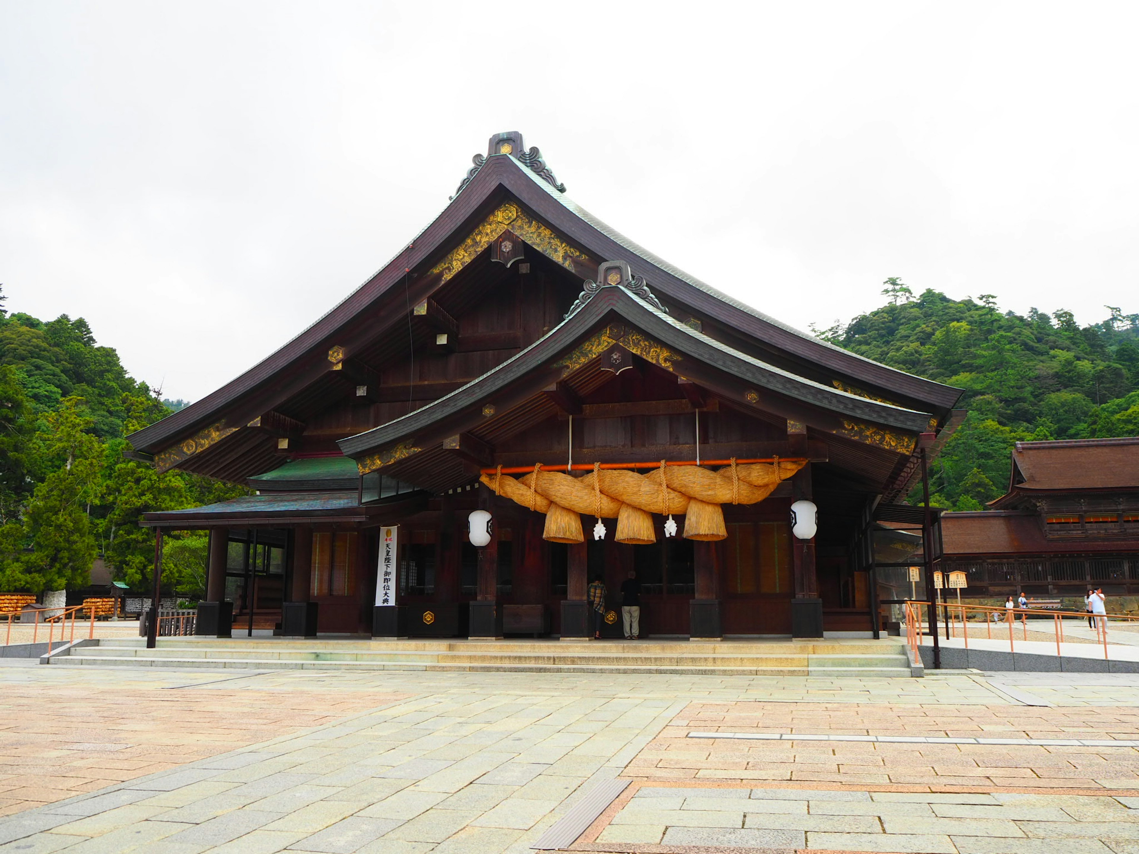 Traditional Japanese shrine building with wooden roof decorative lanterns and surrounding greenery