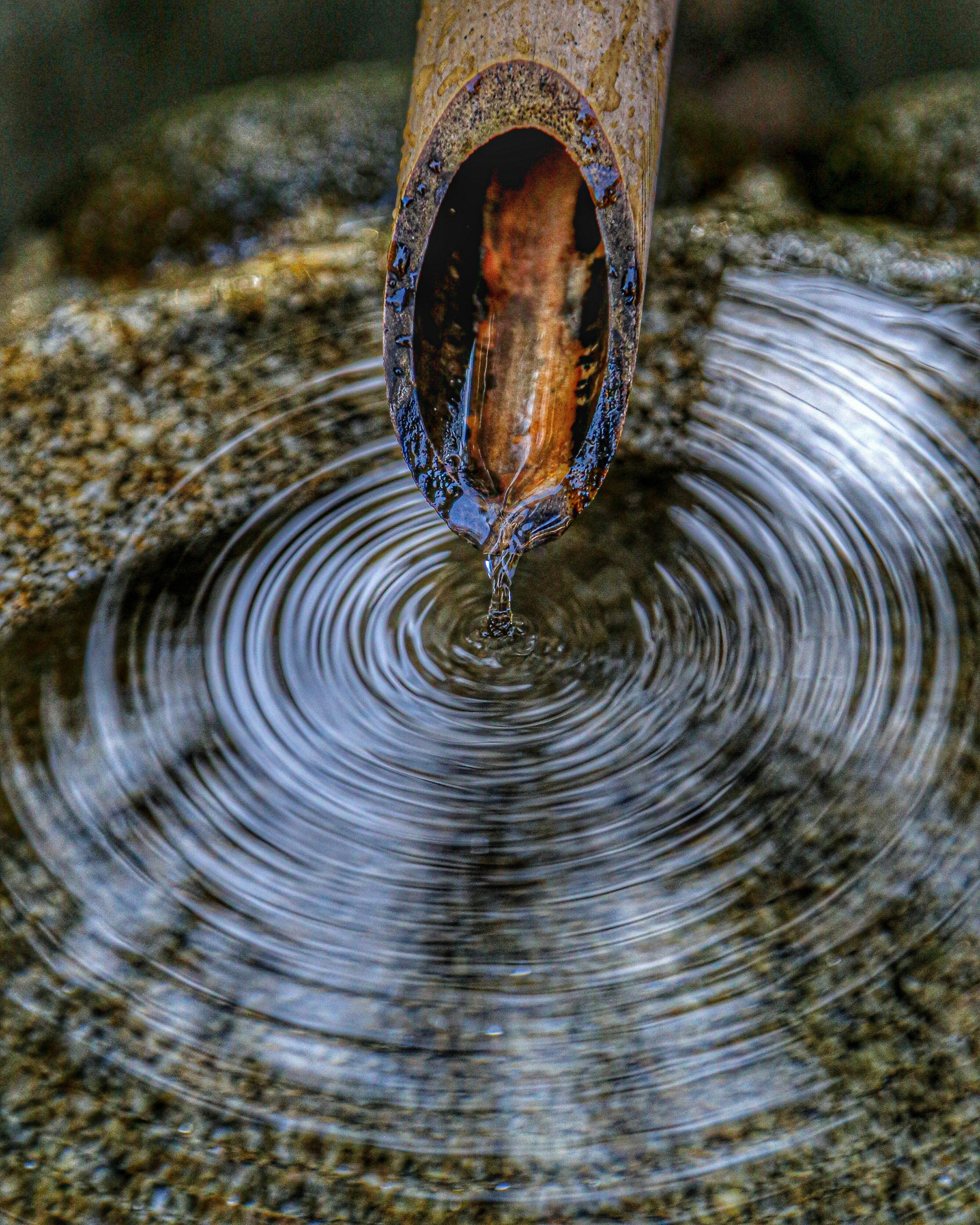 寧靜的場景，水面漣漪和竹水管