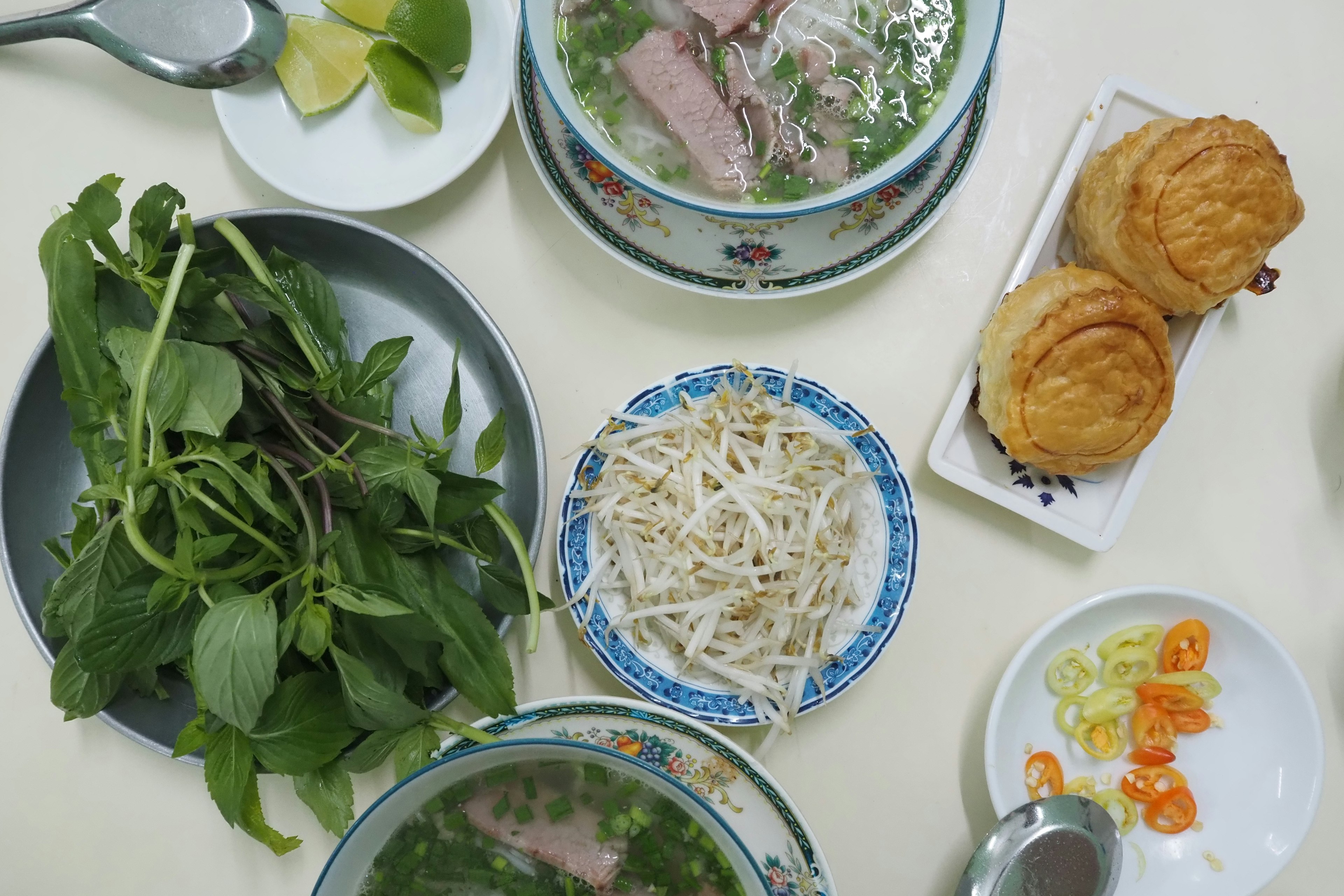 Vietnamesische Pho mit verschiedenen Beilagen auf einem Tisch