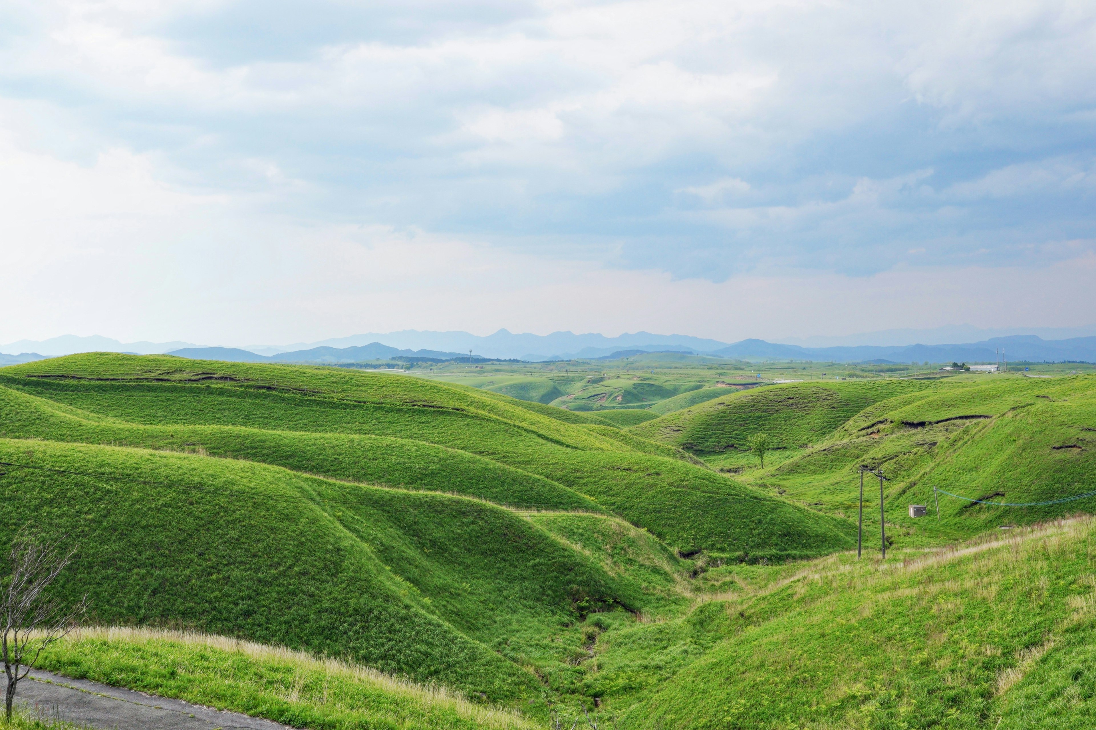 Bukit hijau subur di bawah langit mendung