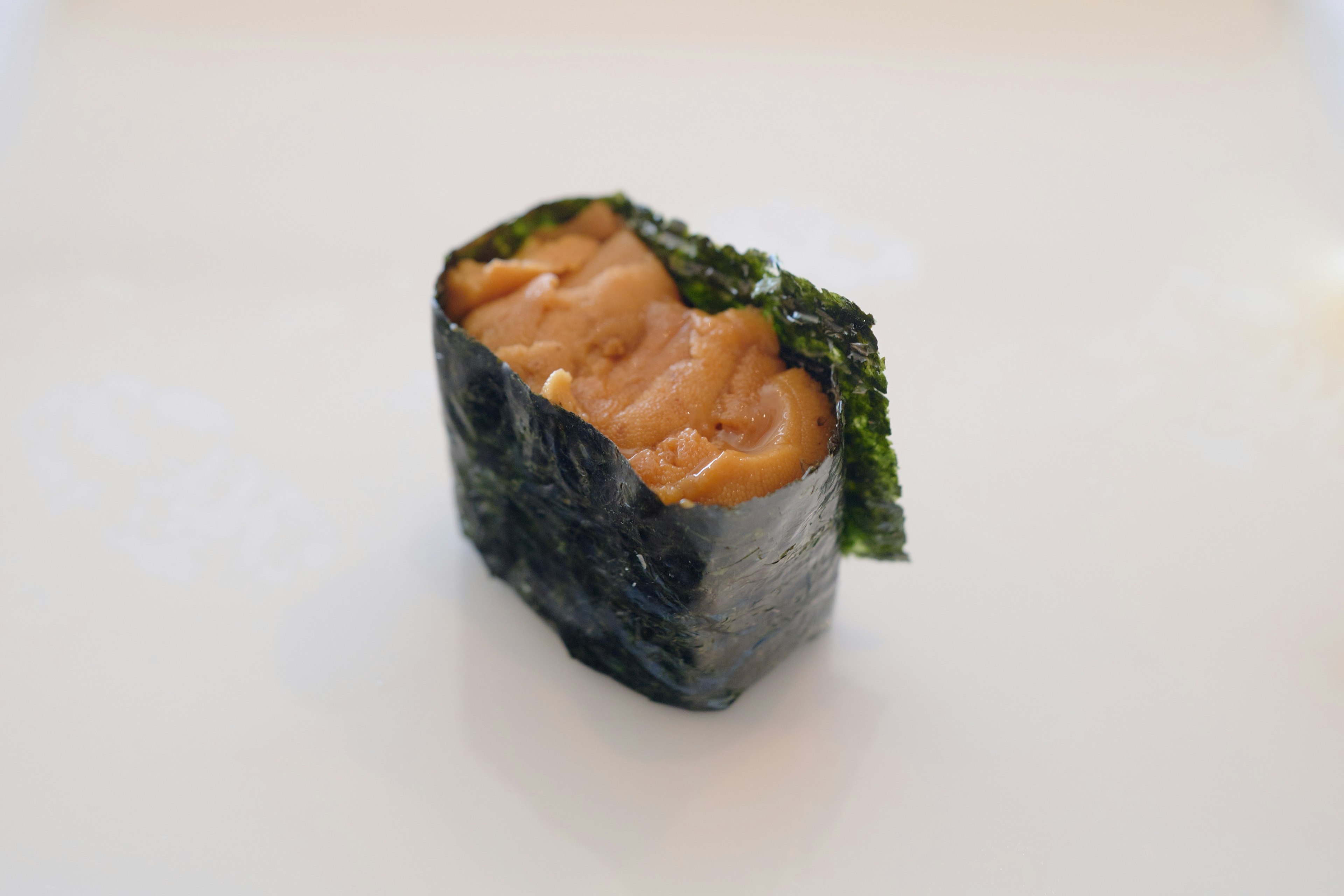 Sushi roll wrapped in nori featuring vibrant orange filling