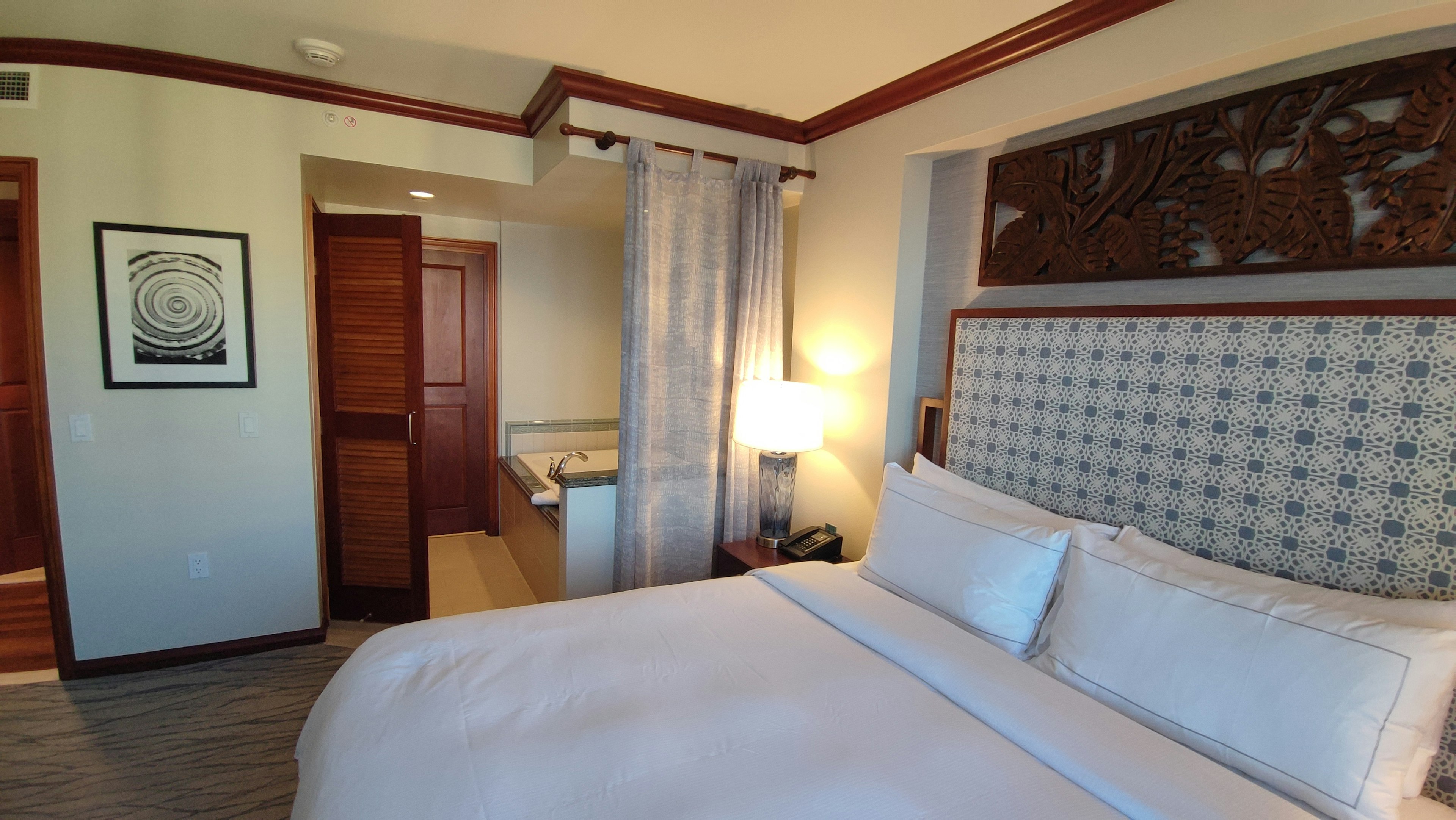 Bright hotel bedroom featuring decorative wall art and wooden door