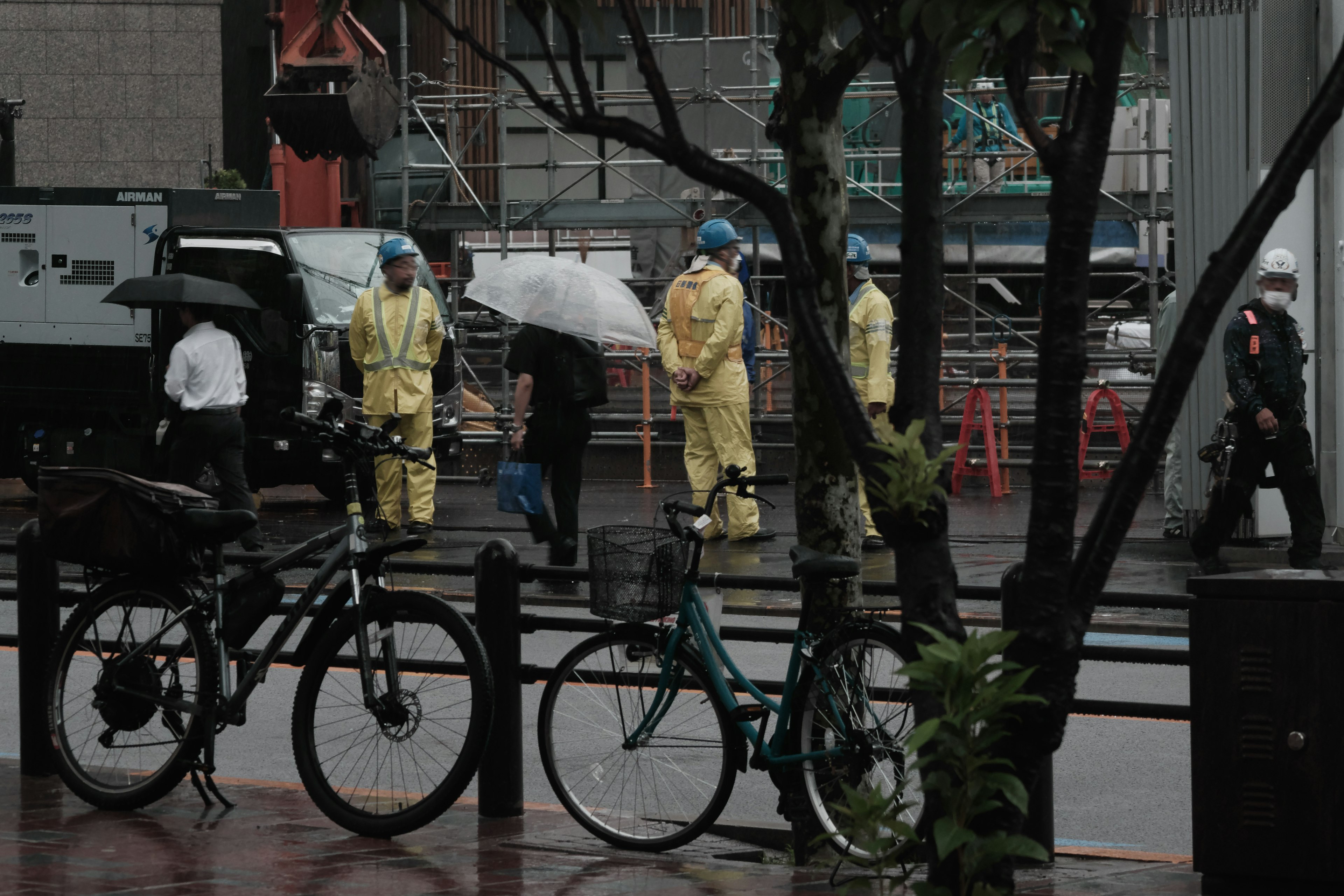 Urban scene with people working in the rain and bicycles