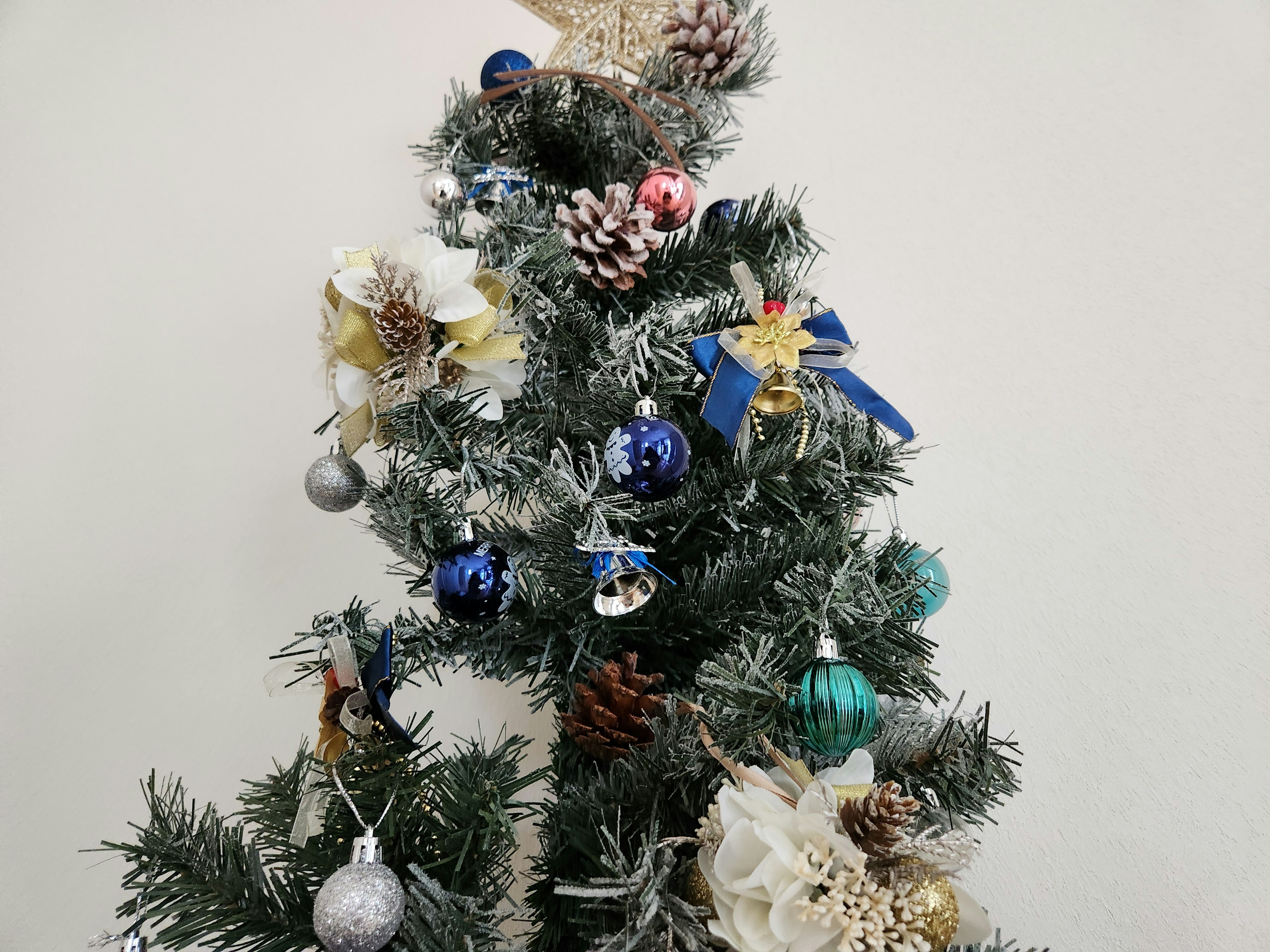 Christmas tree adorned with blue green and red ornaments featuring white snow-like decorations