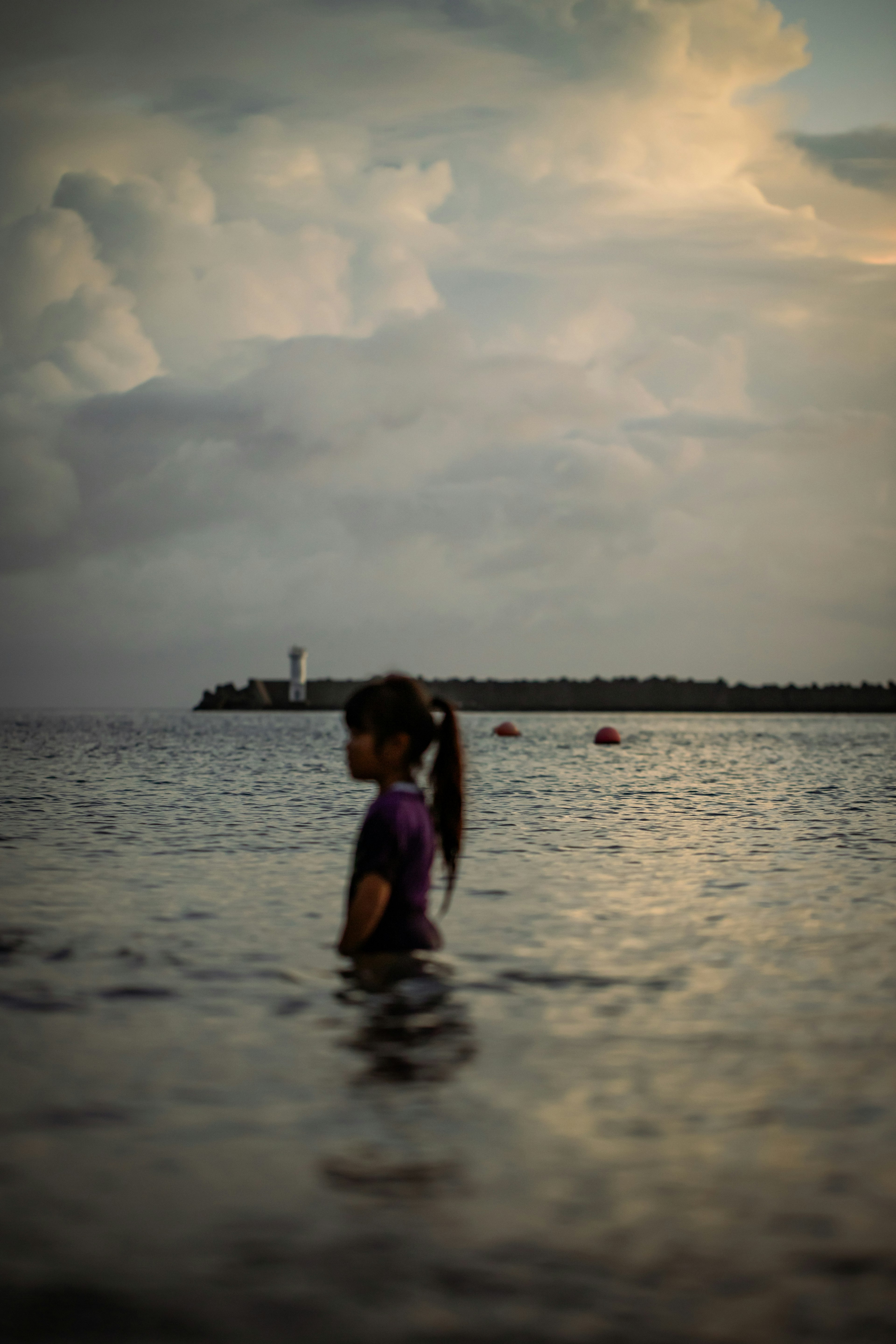 Siluet seorang gadis bermain di laut saat matahari terbenam