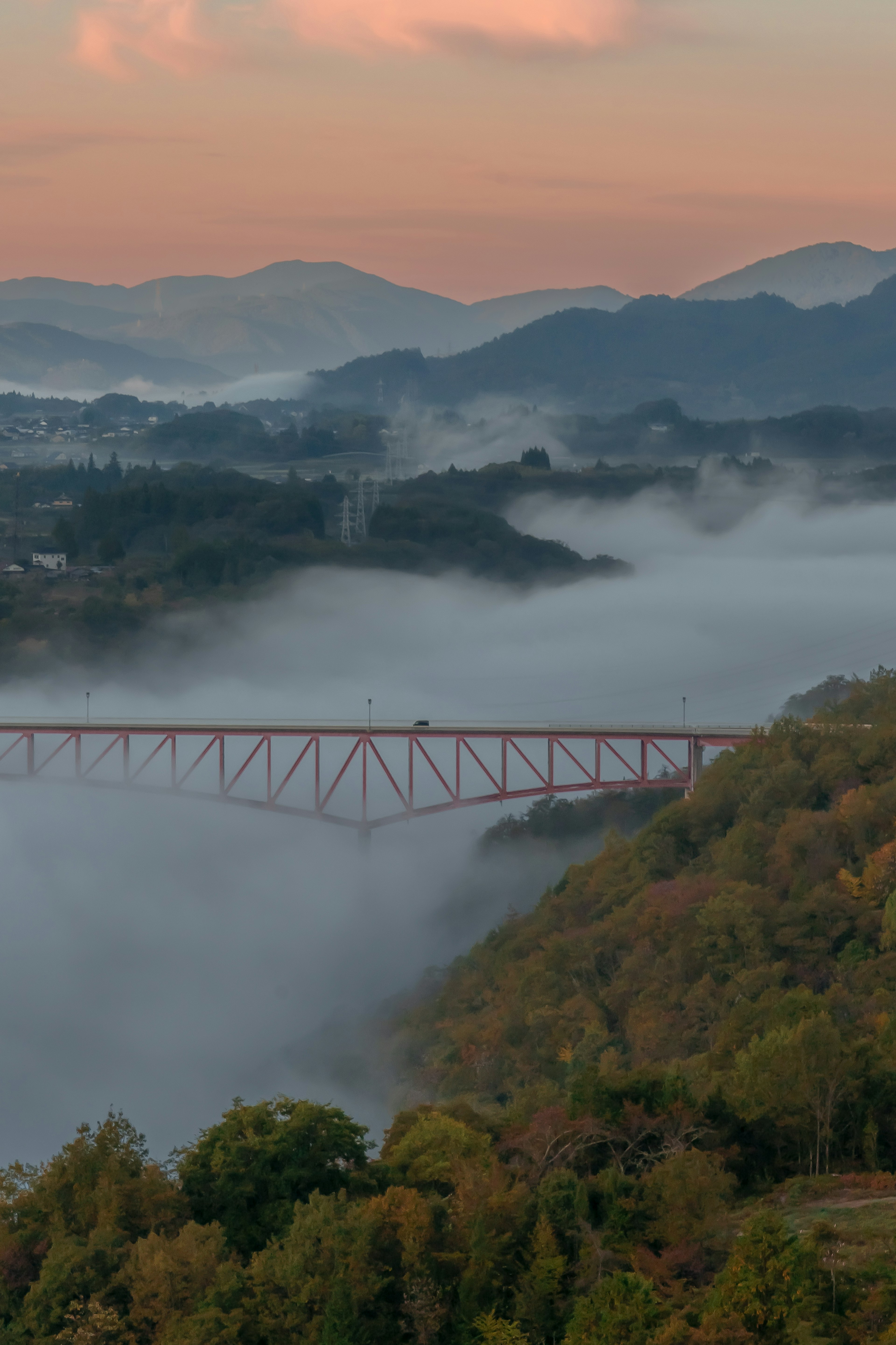 Landschaft mit einer Brücke umgeben von Nebel und Bergen