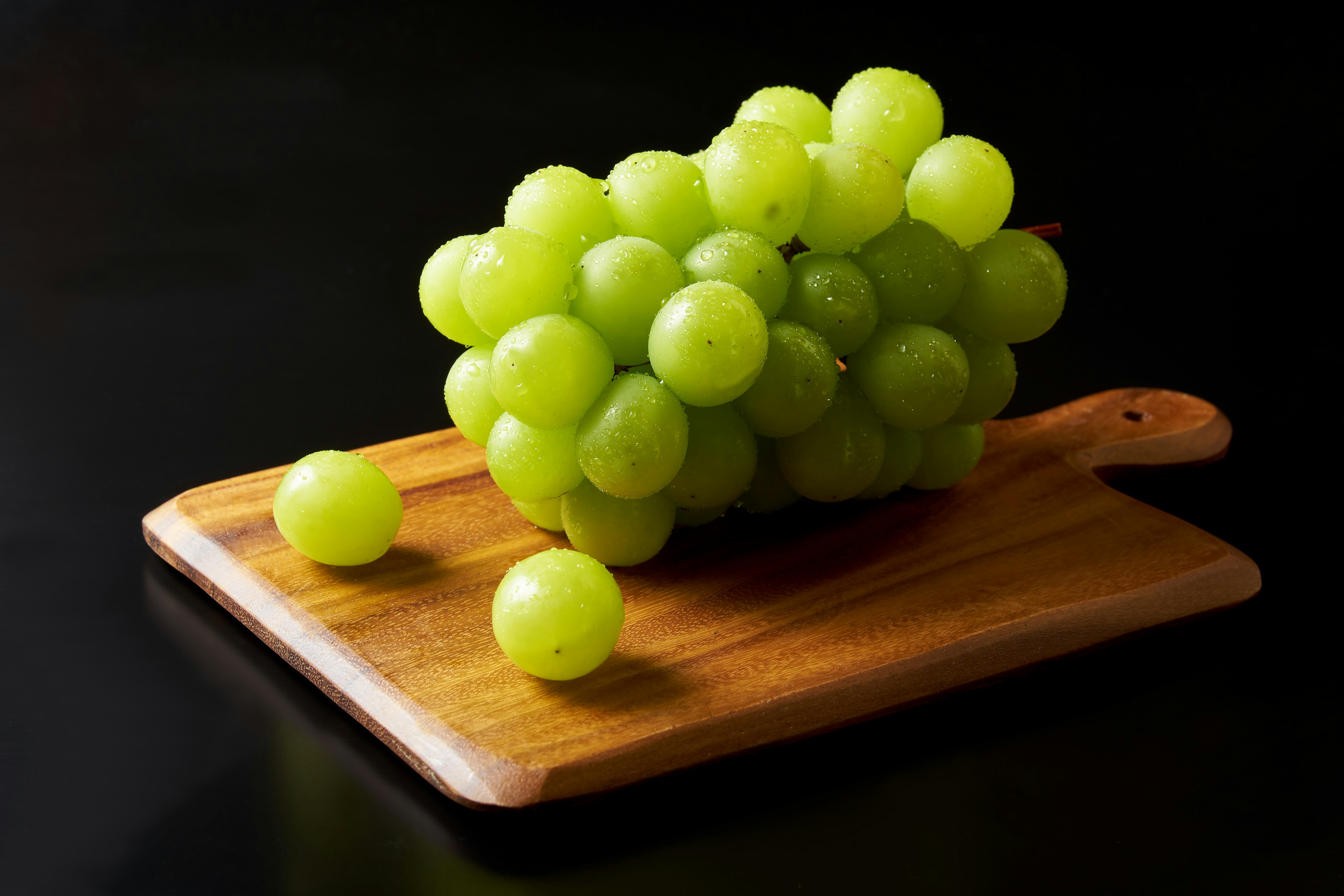 Fresh green grapes clustered on a wooden cutting board