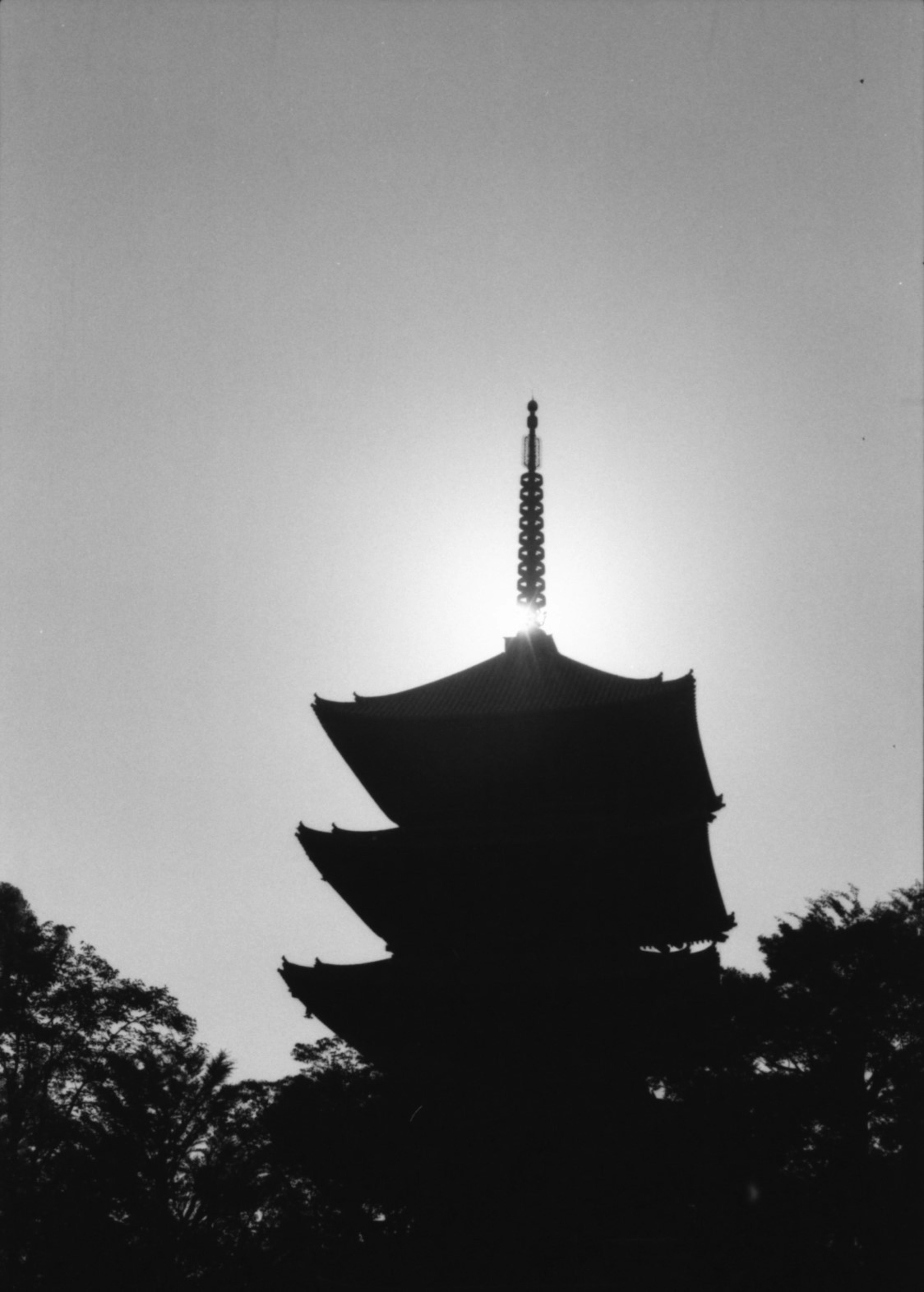 Silhouette of a five-story pagoda with sunlight behind it