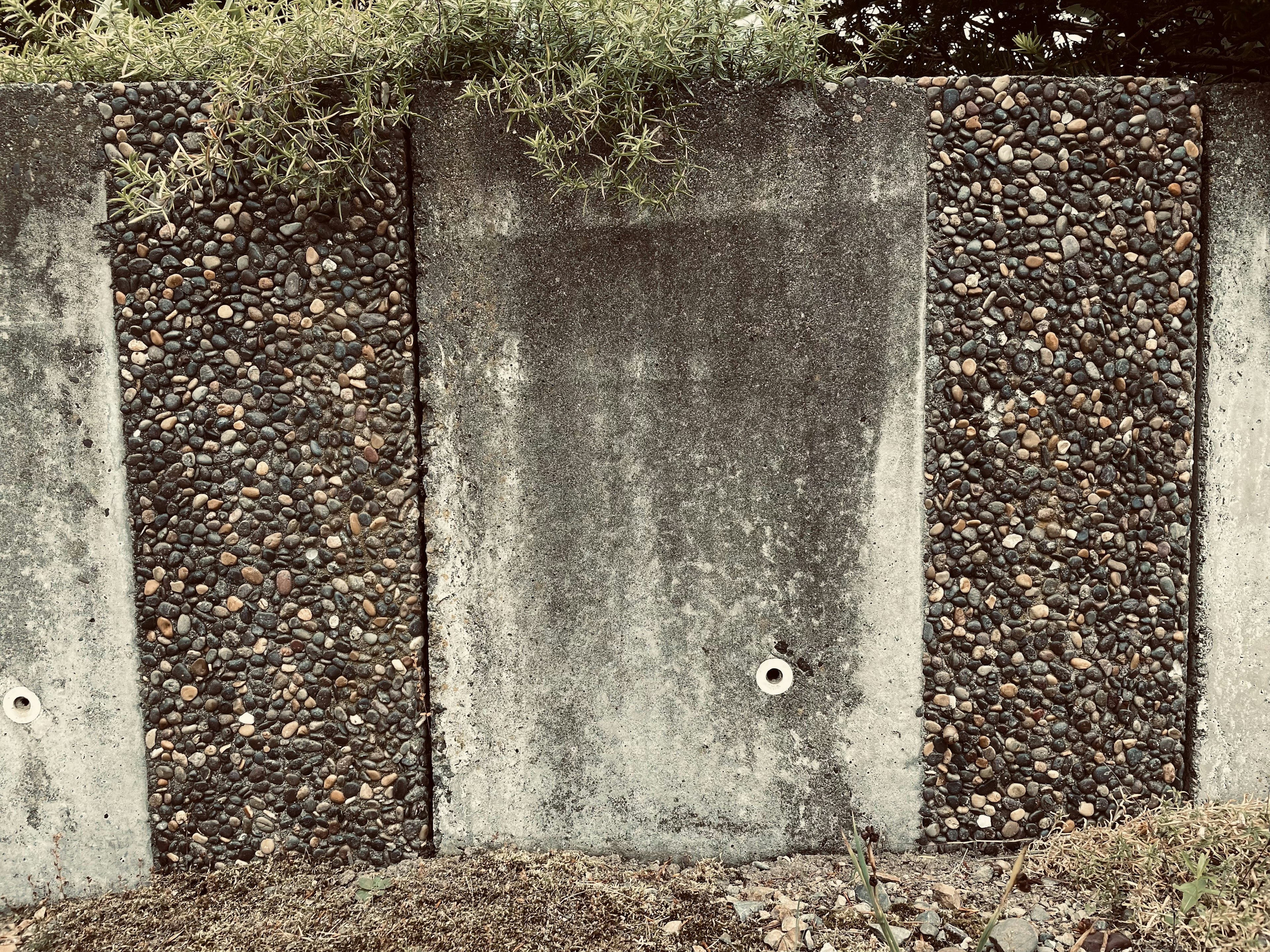 A textured wall featuring concrete panels and decorative stones