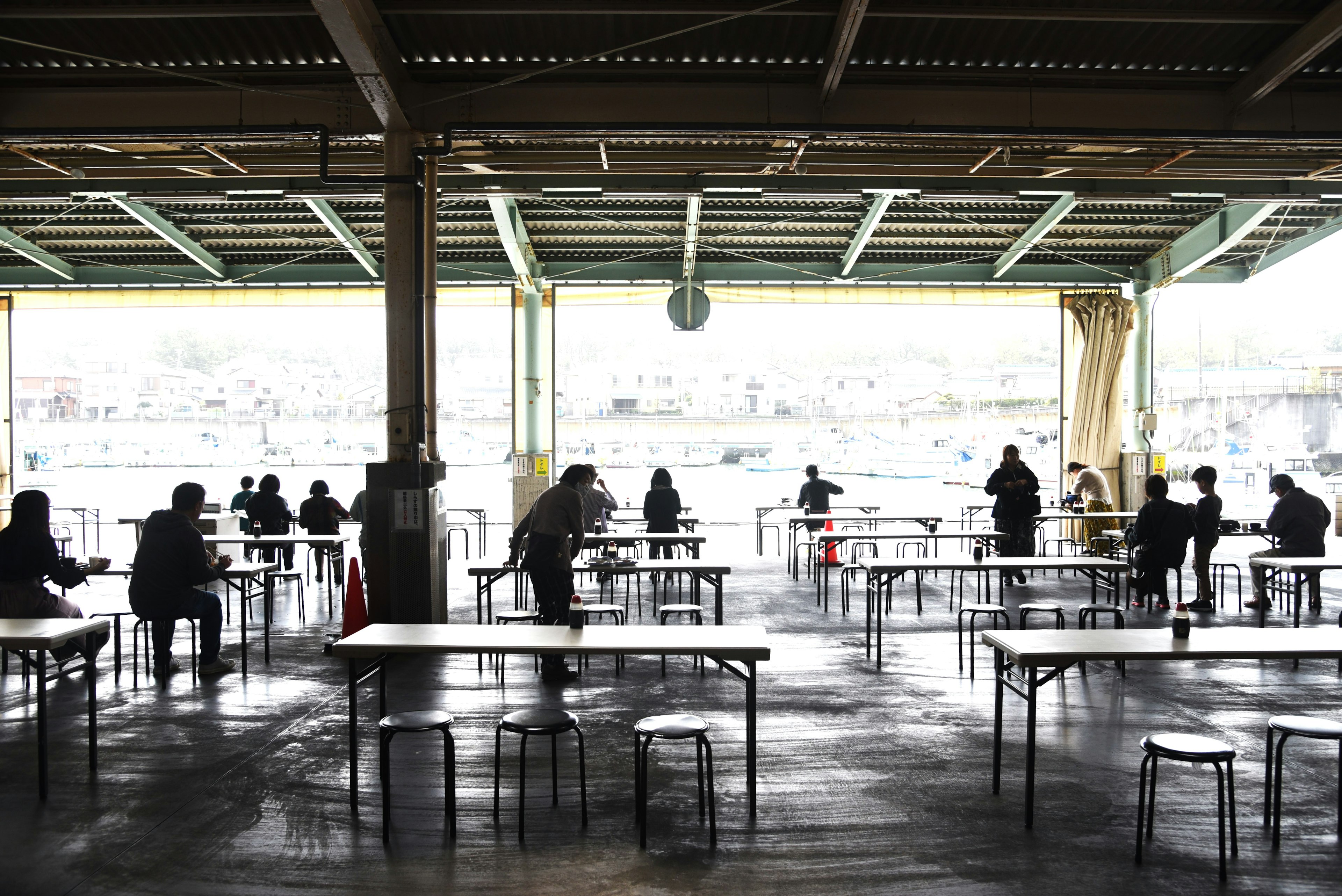 Weitläufiger Raum mit Tischen und Silhouetten von Menschen