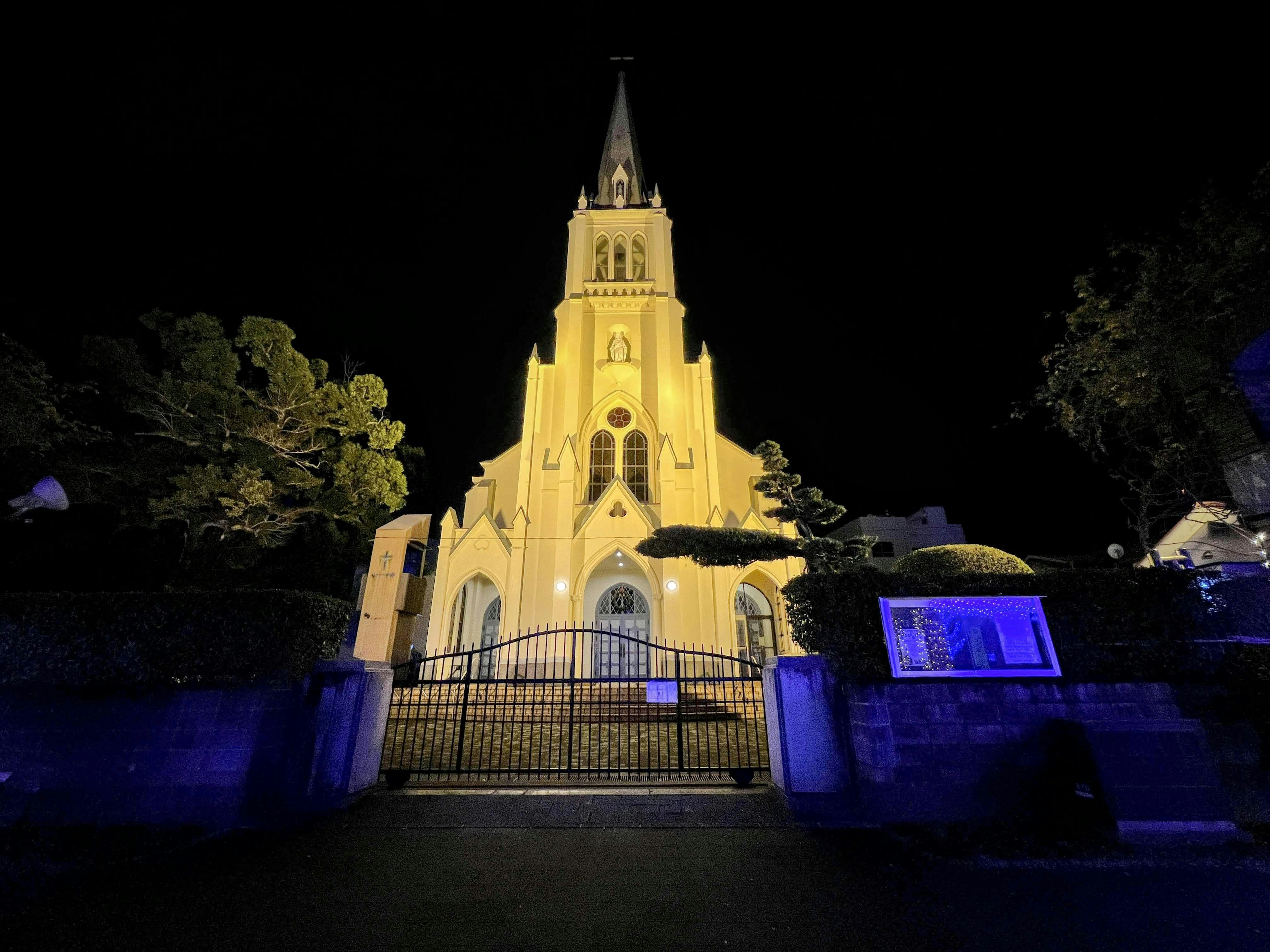 Illuminated church facade at night with iron gate