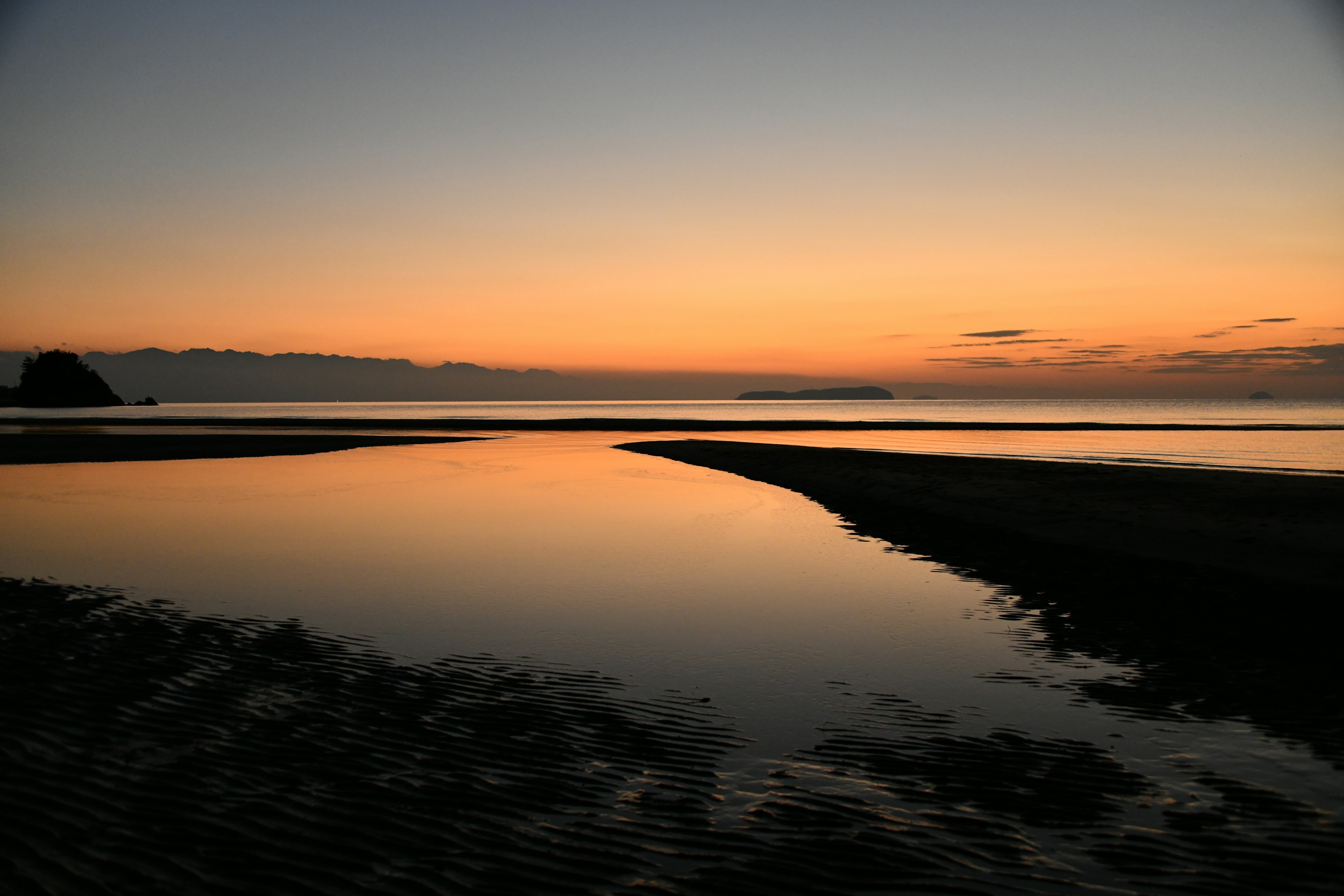 Ruhige Küste bei Sonnenuntergang mit ruhigen Wasserreflexionen