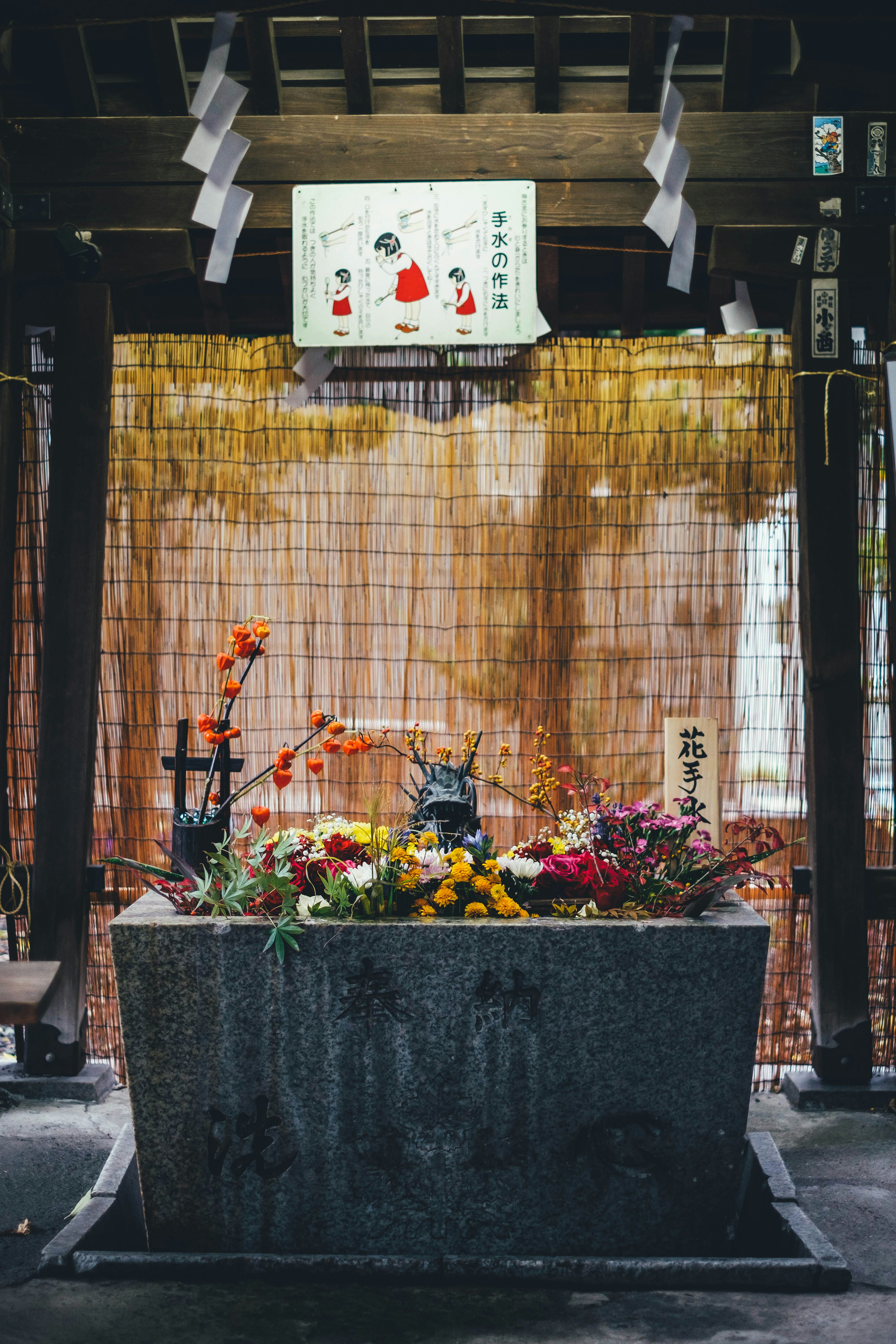 Altar batu yang didekorasi dengan bunga dan layar bambu di latar belakang