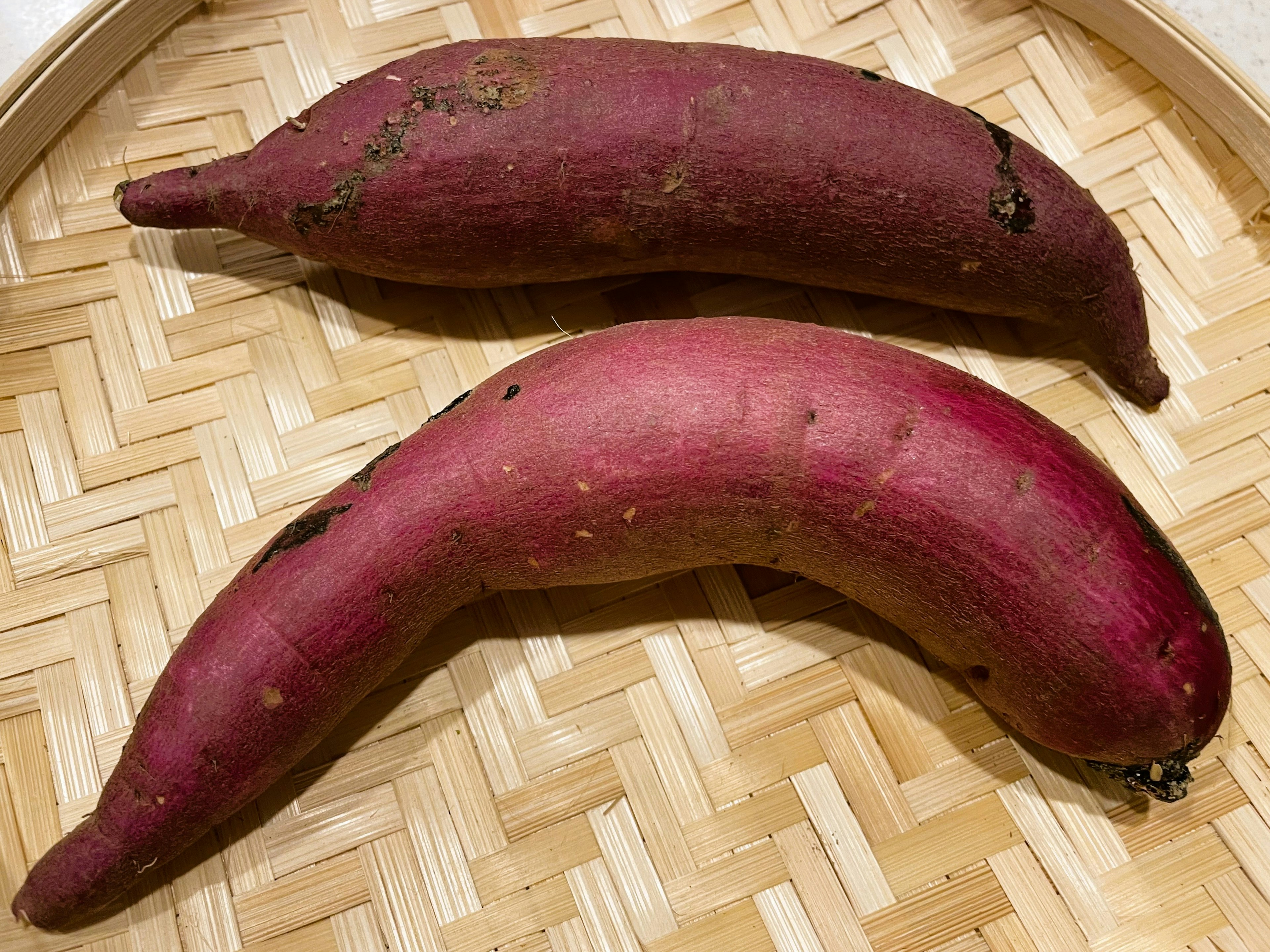 Two purple sweet potatoes placed in a bamboo basket